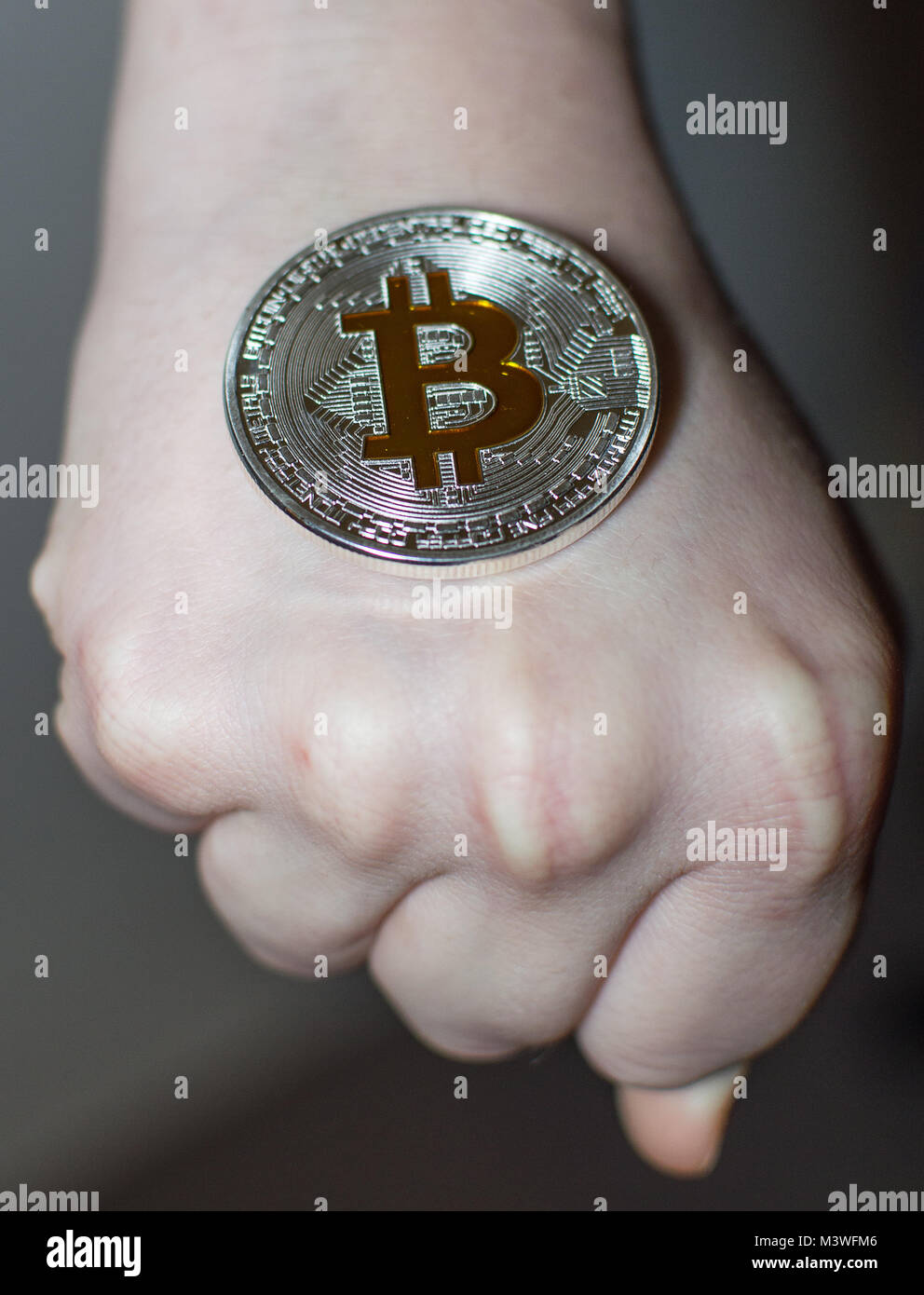 A Bitcoin silver- gold coin in hands. Stock Photo