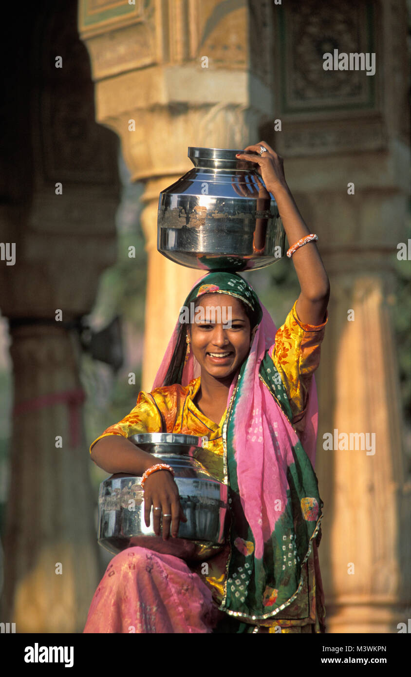 India. Rajasthan. Samode near Jaipur. Woman with water cans, carrying water. Portrait. Stock Photo