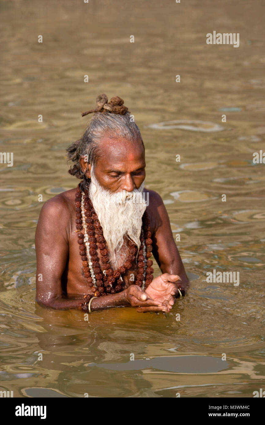 India. Varanasi (Benares). The ghats. Hindu pilgrims bathing and worshipping and to wash away their sins in the Ganges River. Hindu holy man (Sadhu). Stock Photo