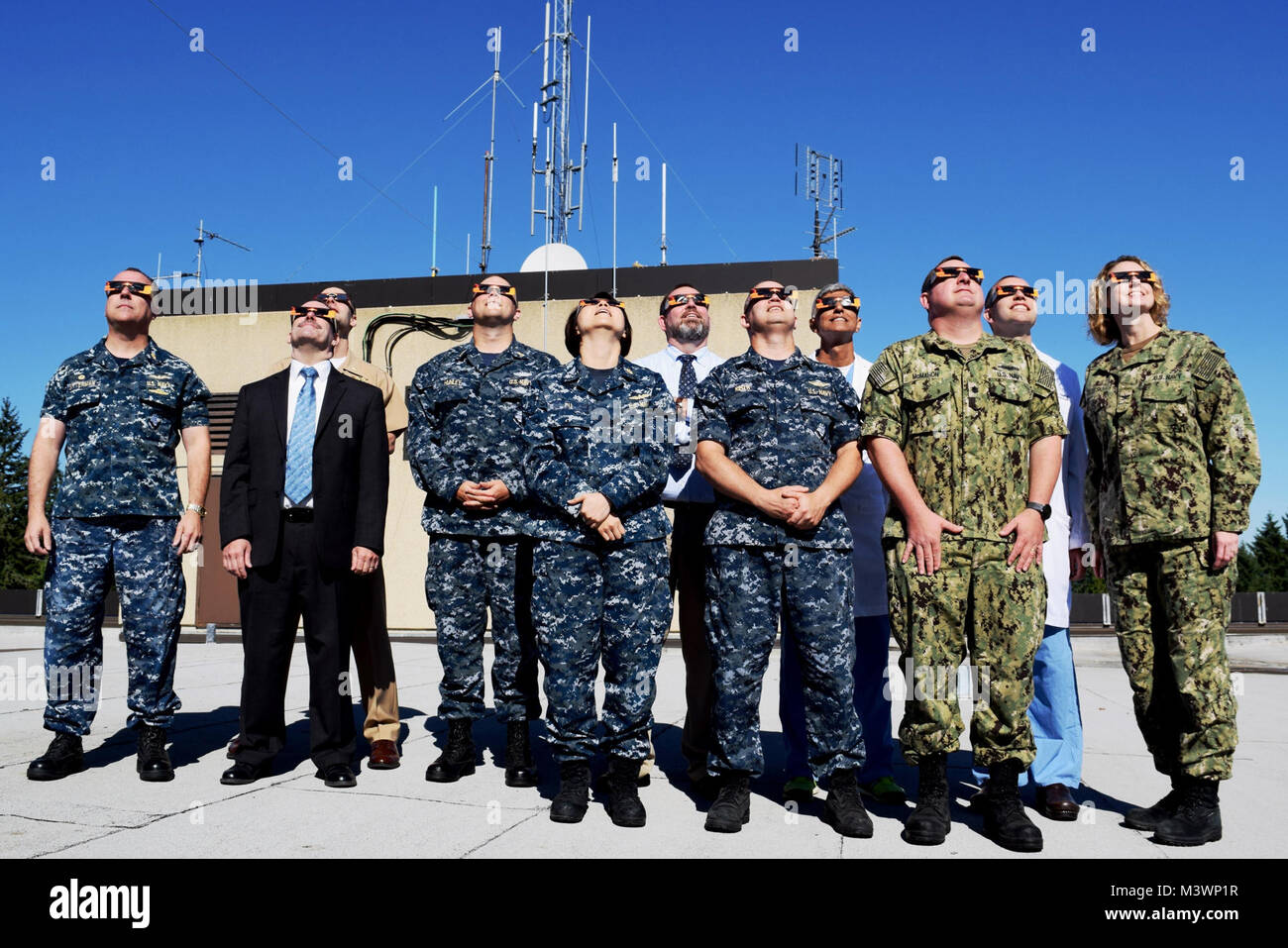 Naval Hospital Bremerton (NHB) Executive Board members take a moment - at 10:22 Pacific Standard Time - to safely view the long-anticipated solar eclipse atop their facility on August 21, 2017. The partial eclipse began around 9:10 a.m. and lasted until approximately 11:40 a.m. In the weeks leading up to the event, NHB's Ophthalmology/Eye Surgery Clinic had consistently reminded patients and staff to remember to not directly look at the eclipse without proper eye protection - not even for a few seconds - due to the concern about temporary and sometimes permanent loss of vision that could occur Stock Photo