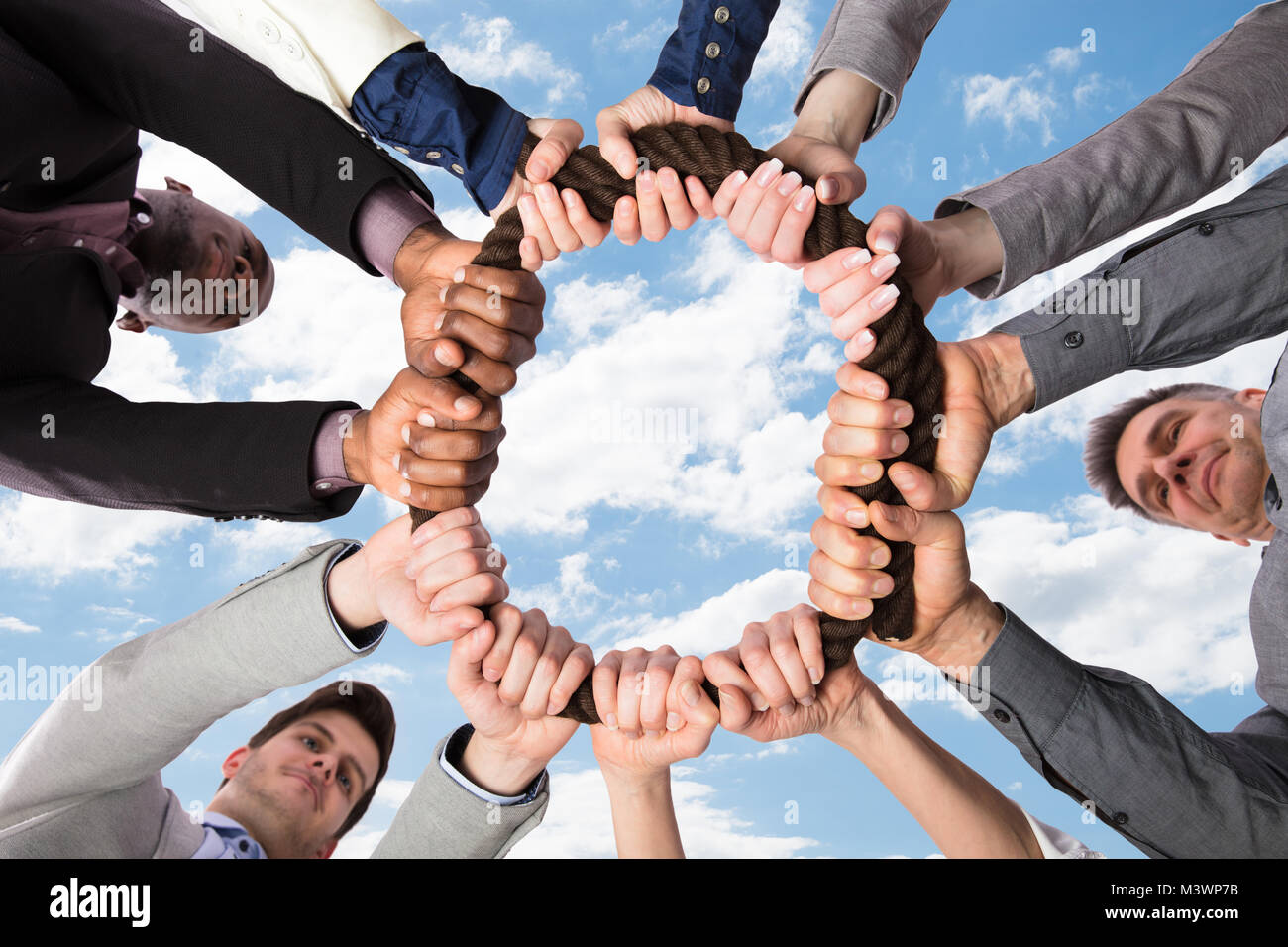 Group Of Businesspeople Standing In Circle Holding Rope Together Stock Photo