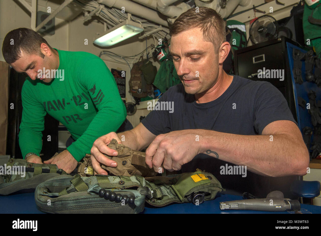 ARABIAN GULF (Oct. 4, 2017) Aircrew Survival Equipmentman 1st Class Donald Bustin, from Laurel, Miss., left, and Aircrew Survival Equipmentman 2nd Class William Lane, from Rutherfordton, N.C., both assigned to the “Bluetails” of Carrier Early Warning Squadron (VAW) 121, perform maintenance on a CMU-36 survival vest in the parachute rigger shop aboard the aircraft carrier USS Nimitz (CVN 68). Nimitz is currently deployed in the U.S. 5th Fleet area of operations in support of Operation Inherent Resolve. While in the region, the ship and strike group are conducting maritime security operations to Stock Photo