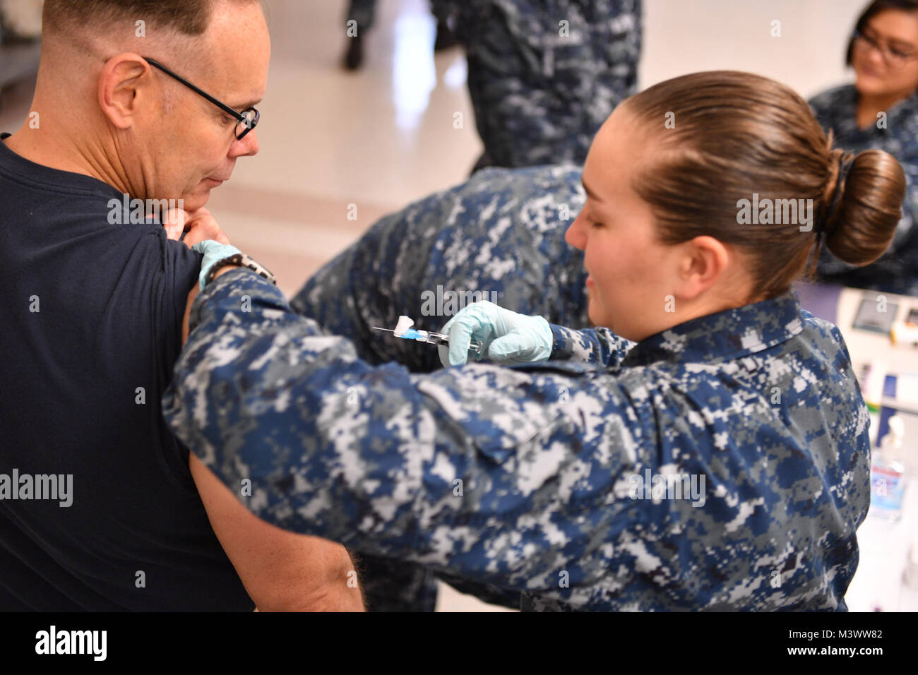 171101-N-JT254-030 SILVERDALE, Wash. (November 01, 2017) Hospital Corpsman 2nd Class Claire Anderson, assigned to Naval Hospital Bremerton, administers a flu vaccine to Lieutenant Commander Don Rogers, chaplain assigned to Naval Submarine Support Center Bangor.  The influenza, or “flu”, has the potential to adversely impact Navy force readiness and mission execution, and vaccination is mandatory for DoD uniformed personnel. (U.S. Navy photo by Mass Communication Specialist Seaman Christopher Jahnke) 171101-N-JT254-030 by Naval Base Kitsap (NBK) Stock Photo