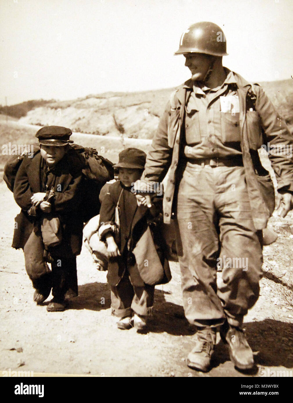 80-G-427969:  Korean War, 1950-1953.   Navy Chaplain Lieutenant Junior Grade R.L. Patton, (ChC), USN, of Tulsa, Oklahoma, serving with First Marine Division leads two small boys back to their liberated homes at Hongchon, Korea.  Photographed March 20, 1951.  Official U.S. Navy Photograph, now in the collections of the National Archives.  (2018/01/10). 80-G-427969_24749398297_o Stock Photo