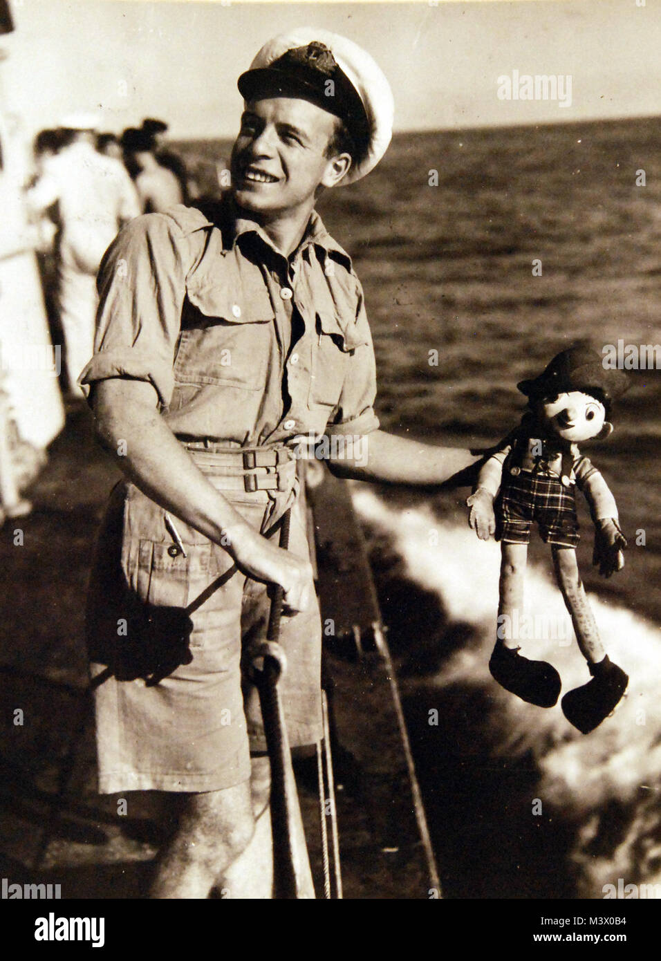 80-G-316324:  Lieutenant C. Murdock on destroyer of the Royal Navy (British) fleet with doll mascot “Wee Willie”.   Photograph received April 24, 1945.  Official U.S. Navy Photograph, now in the collections of the National Archives.  (2018/01/31). 80-G-316324 26136262838 o Stock Photo
