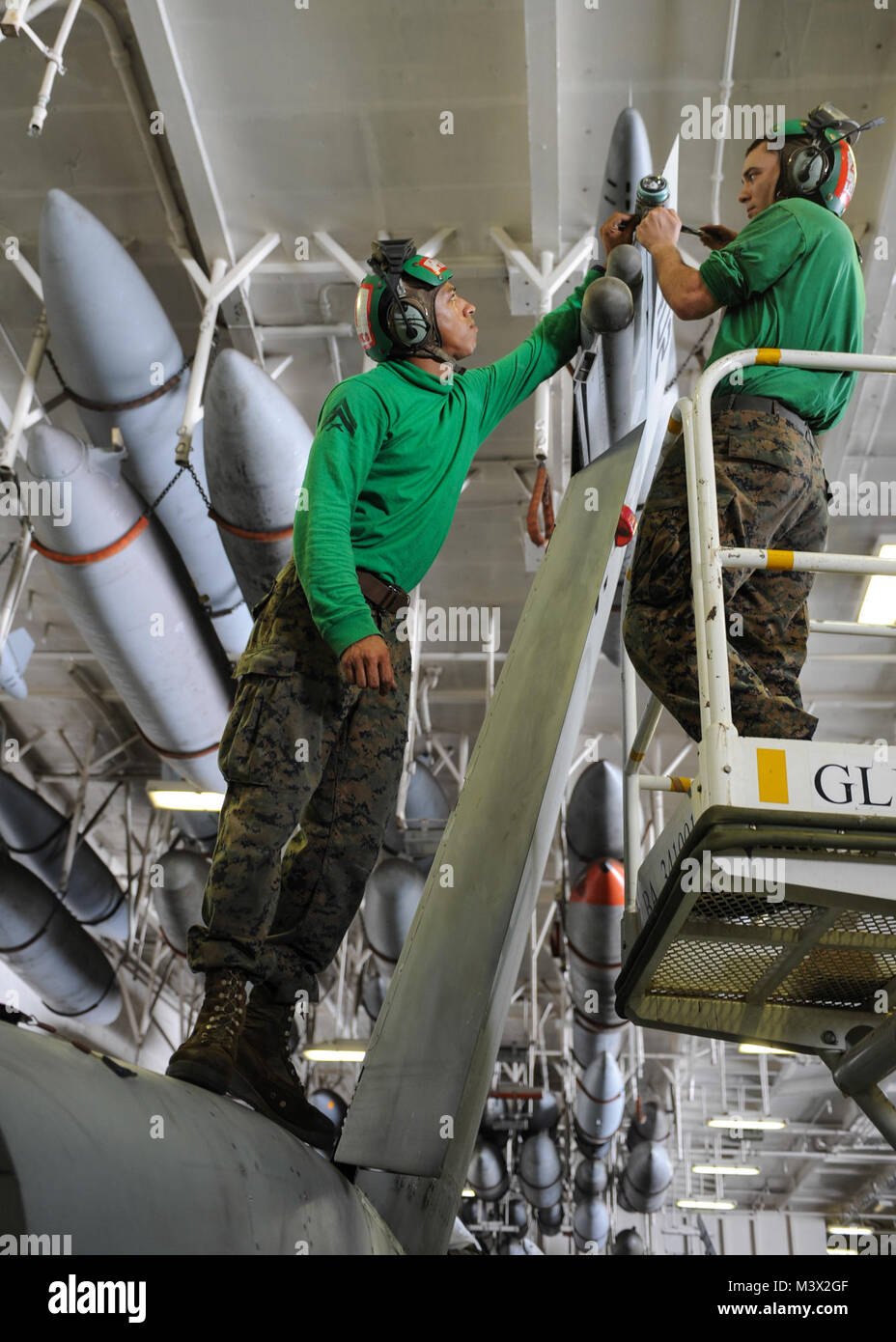 130715-N-KE148-125 GULF OF OMAN (July 15, 2013) – Cpl. Jorge Nieves from Puerto Rico, and Lance Cpl. Haldis Tucker from Wilmington, Pa., work on the tail position light on an F/A-18C Hornet from the "Death Rattlers" of Marine Fighter Attack Squadron (VMFA) 323 in the hangar bay of the aircraft carrier USS Nimitz (CVN 68). Nimitz Strike Group is deployed to the U.S. 5th Fleet area of responsibility conducting maritime security operations, theater security cooperation efforts and support missions for Operation Enduring Freedom.  (U.S. Navy photo by Mass Communication Specialist 3rd Class Chris B Stock Photo