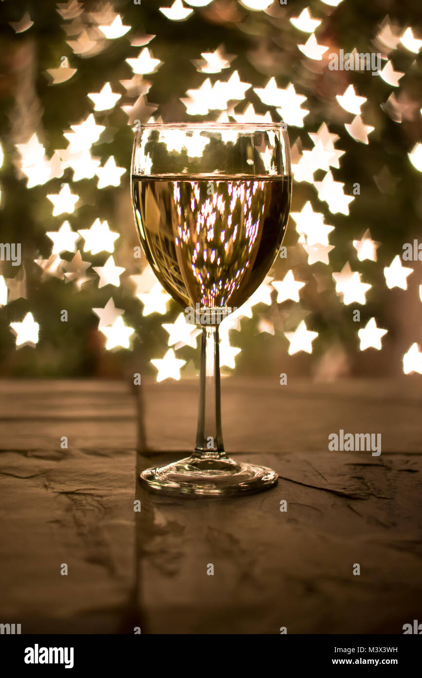 Cheers to wine lovers everywhere! Star-shaped bokeh with Christmas tree in background. Stock Photo