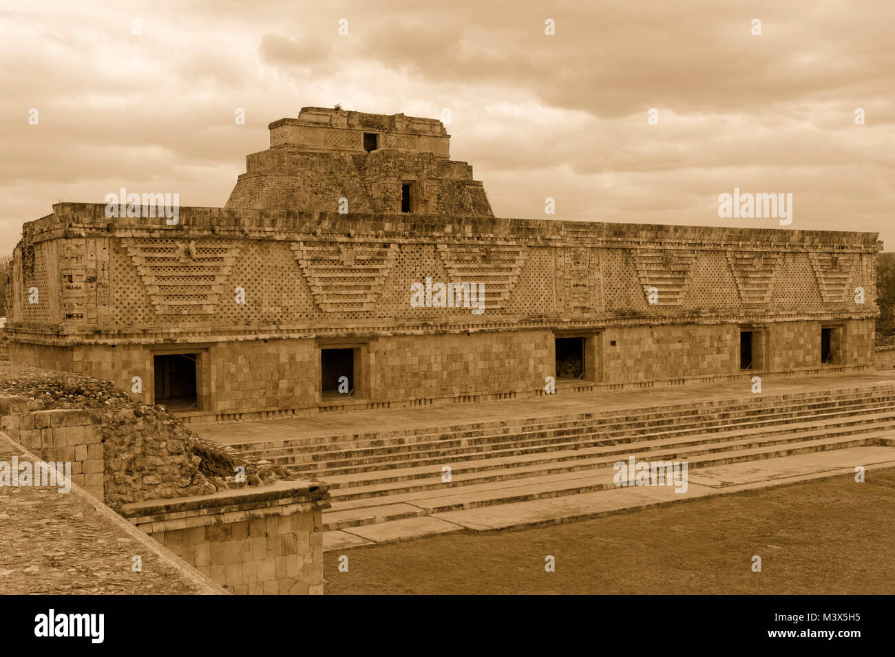 Sepia tone east building of the Nunnery Quadrangle with Pyramid of the Magician at the Mayan ruins of  Uxmal, Yucatan, Mexico Stock Photo