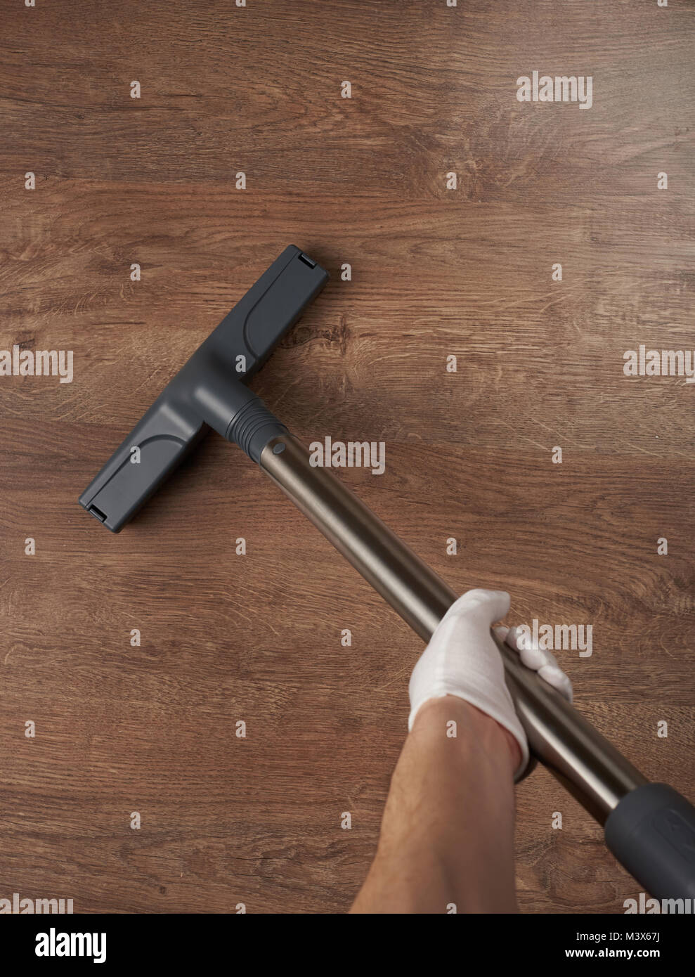 Hand hold vacuum cleaner close up. Cleaning wooden surface Stock Photo