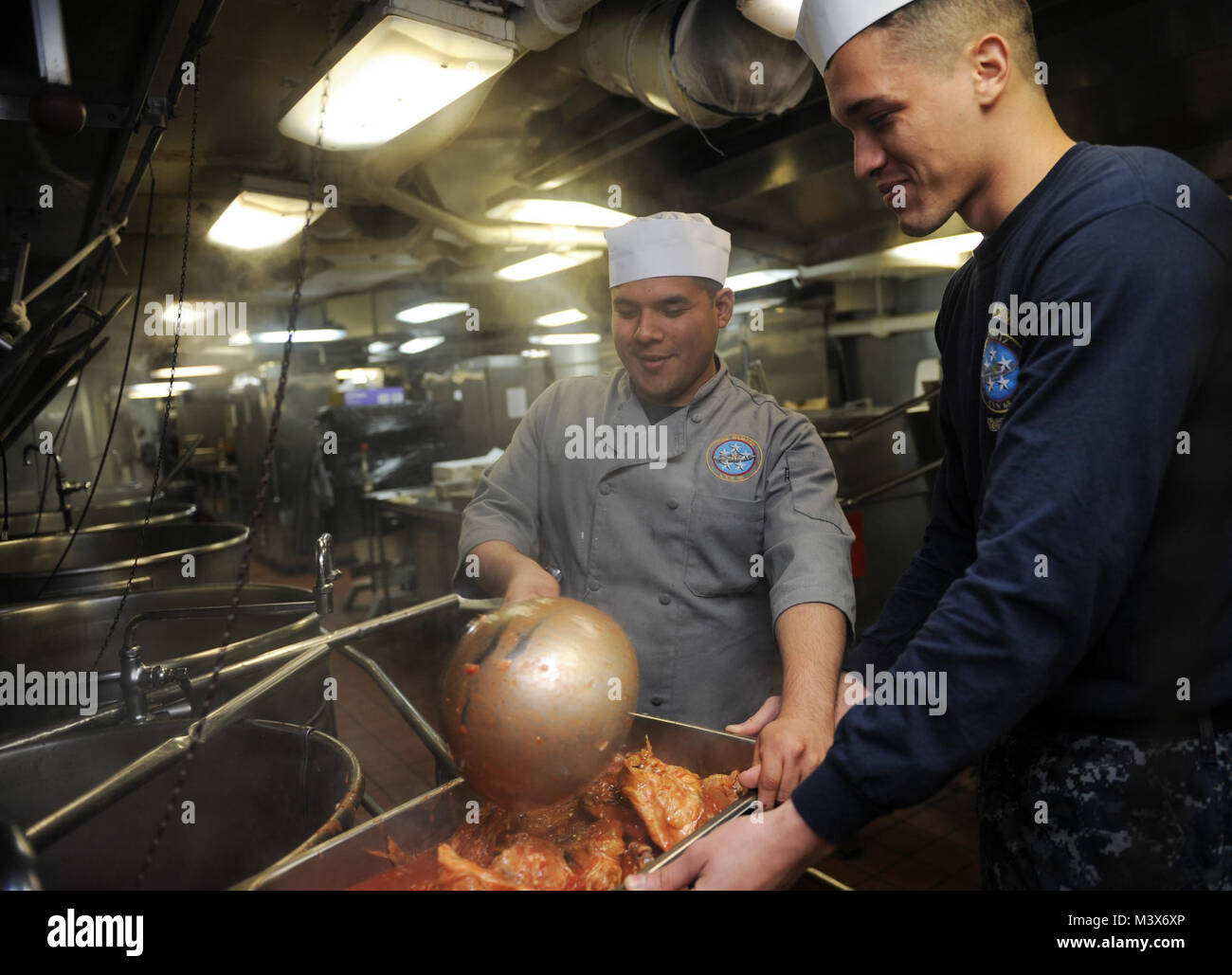 EVERETT, Wash. (March 20, 2014) –  Culinary Specialist Seaman Jose Gomez, left, and Aviation Maintenance Administrationman Airman Recruit Rolando Casana scoop pork onto a pan in the mess decks on board the aircraft carrier USS Nimitz (CVN 68). Nimitz recently returned to its homeport of Naval Station Everett after a nine-month deployment. (U.S. Navy photo by Mass Communication Specialist Seaman Kelly M. Agee/Released) 140320-N-AZ866-055.JPG by USS NIMITZ (CVN 68) Stock Photo
