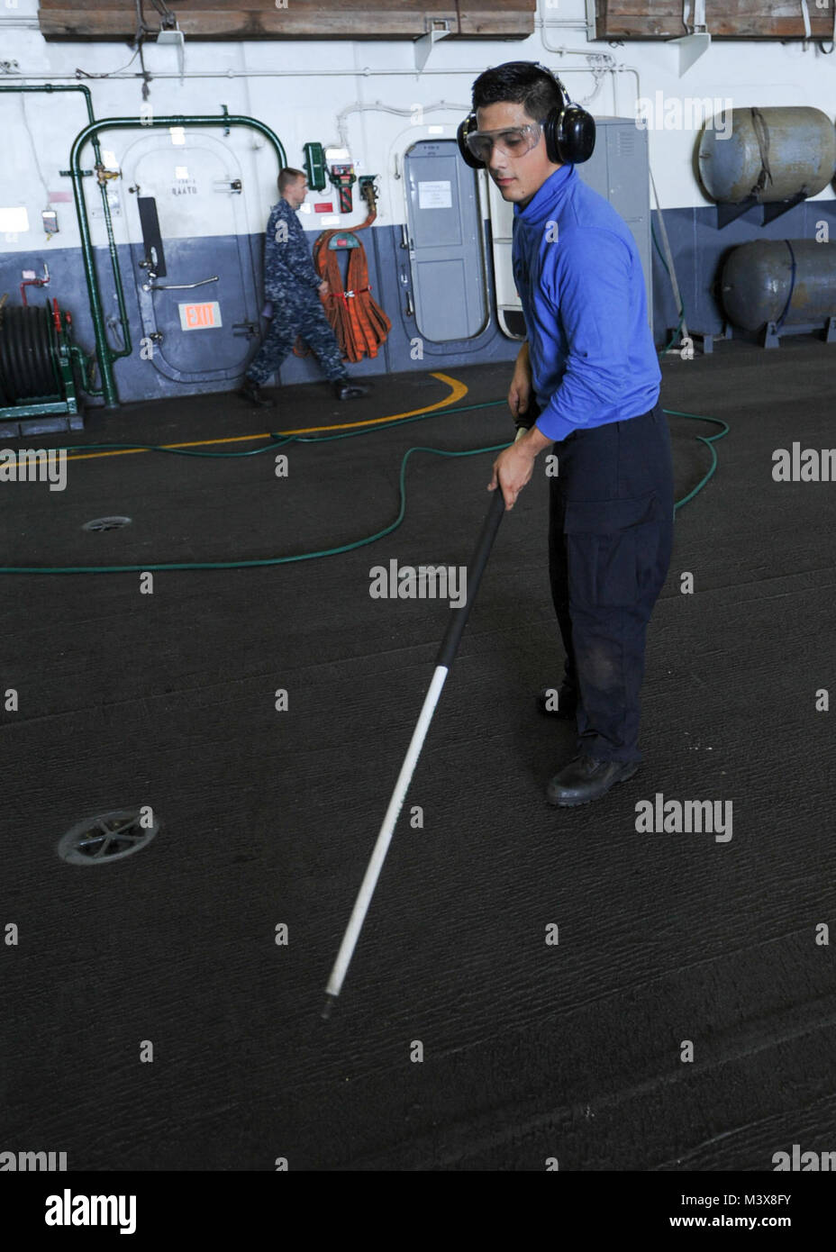 PACIFIC OCEAN (July 19, 2014) Aviation Boatswain’s Mate (Handling) Airman Cesar J. Martinez, of Anaheim, Calif., uses an air hose to clean the hangar bay of the aircraft carrier USS Nimitz (CVN 68). Nimitz is currently underway conducting carrier qualifications. (U.S. Navy photo by Mass Communication Specialist 3rd Class Linda S. Swearingen/Released) 140719-N-BJ752-055.jpg by USS NIMITZ (CVN 68) Stock Photo