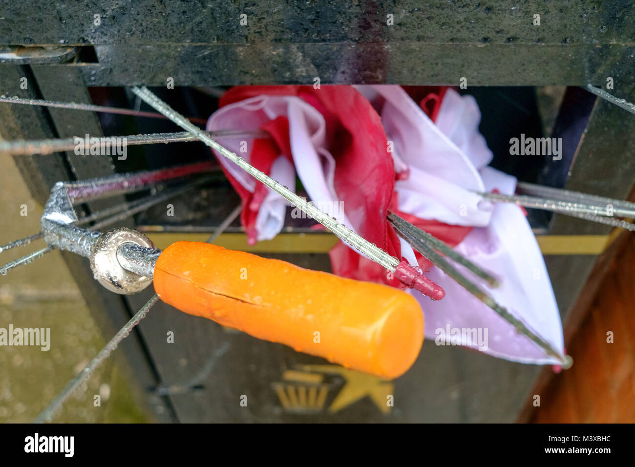 Broken metal frames umbrella stuffed into municipal litter bin. Carmarthenshire. Wales. UK. Stock Photo