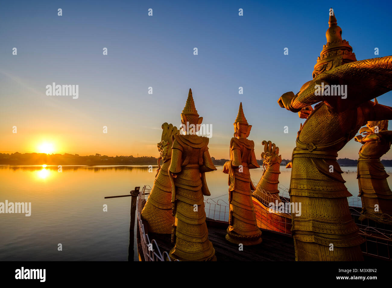 Golden statues are decorating the Pyi Gyi Mon Royal Barge, a swimming restaurant, floating on Kandawgyi Lake at sunrise Stock Photo