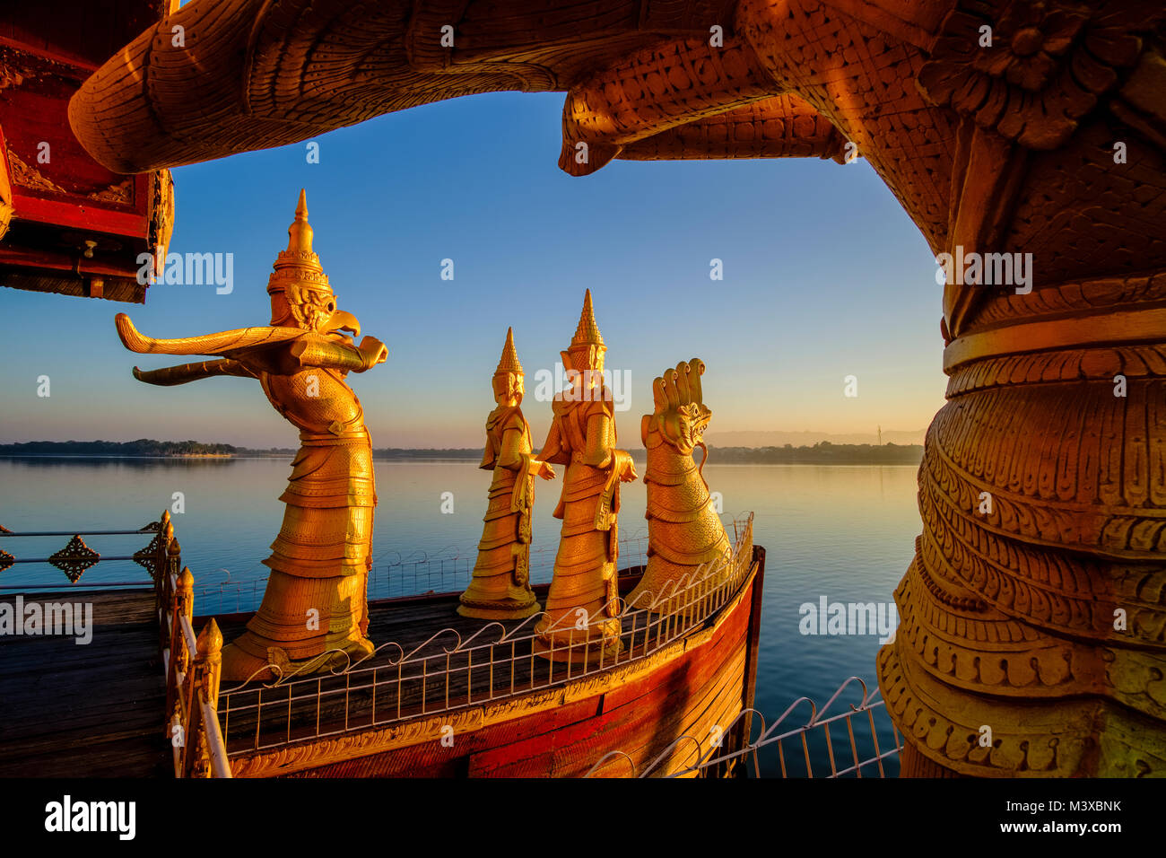 Golden statues are decorating the Pyi Gyi Mon Royal Barge, a swimming restaurant, floating on Kandawgyi Lake at sunrise Stock Photo