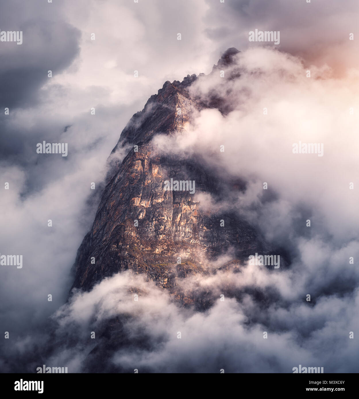 Majestical mountains in clouds in overcast evening in Nepal. Landscape with beautiful high rocks and dramatic cloudy sky with sunlight at sunset. Natu Stock Photo