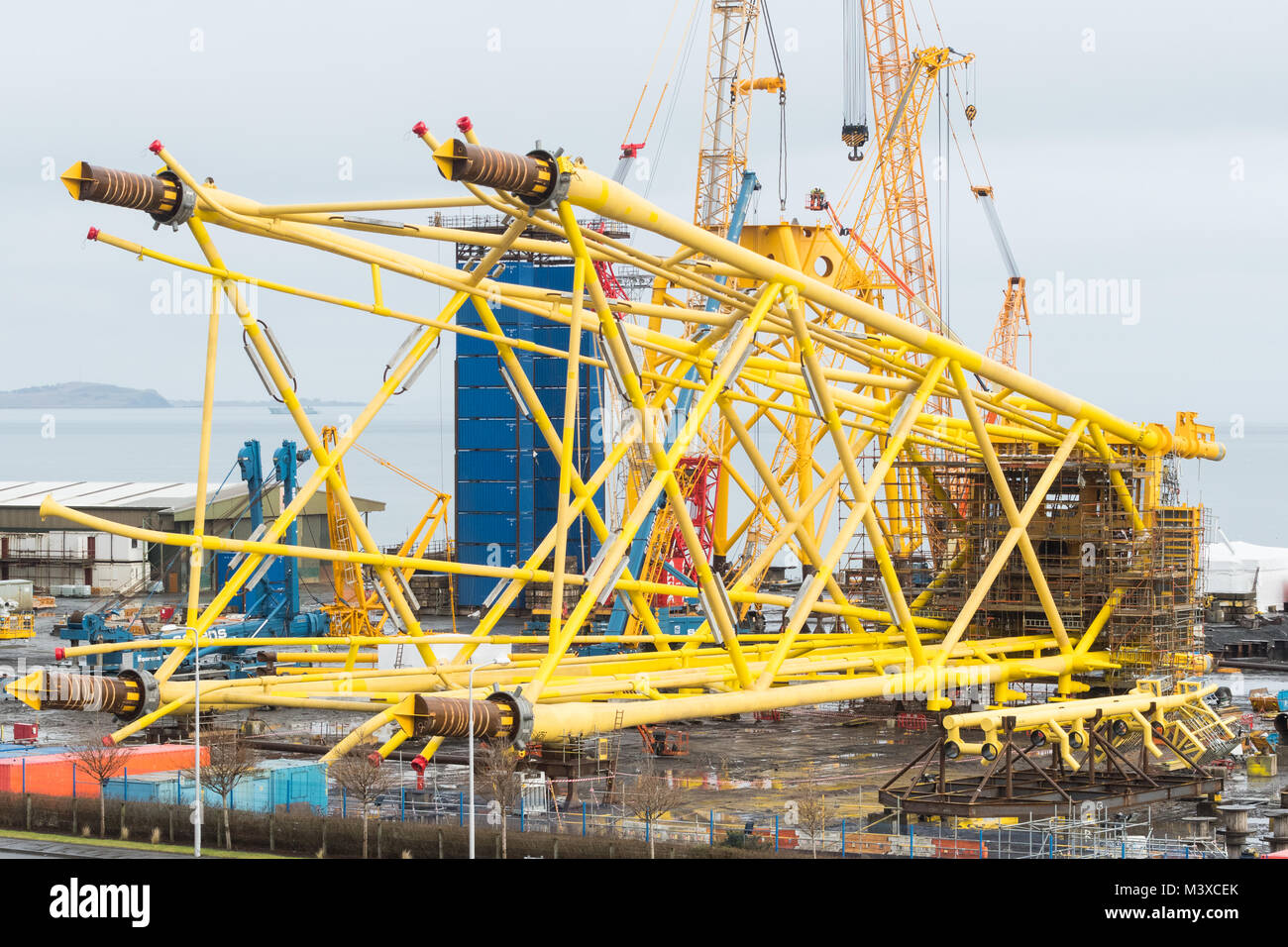 BiFab - Burntisland Fabrications Methil Burntisland Yard, Fife, Scotland, UK - workers being lifted by crane dwarfed by the yellow sub-sea jackets Stock Photo