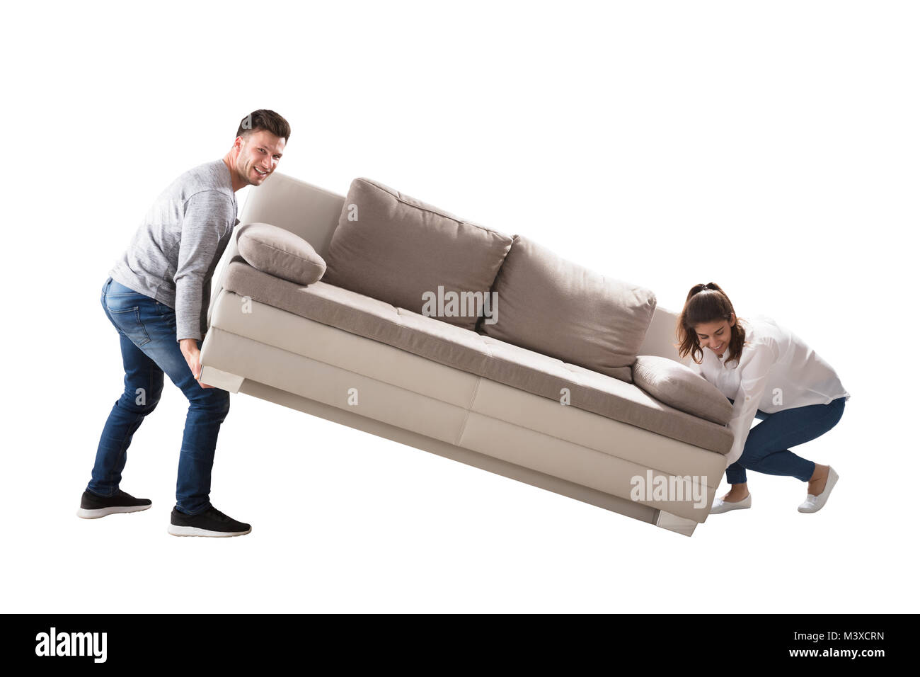 Happy Young Couple Lifting Sofa On White Background Stock Photo