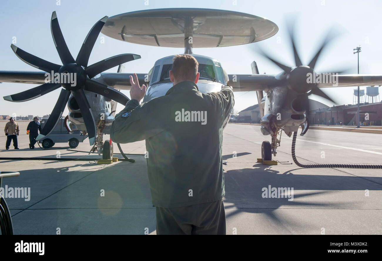 U.S. Navy Lt. Daniel Marsik, E-2D Hawkeye pilot, signals to his co-pilot to start the aircraft’s left engine during a hot pit refueling, Jan. 24, 2018, at Scott Air Force Base, Illinois. The E-2D was Scott’s first hot pit refueling on a fixed-wing aircraft. (U.S. Air Force photo by Airman 1st Class Tara Stetler) Stock Photo