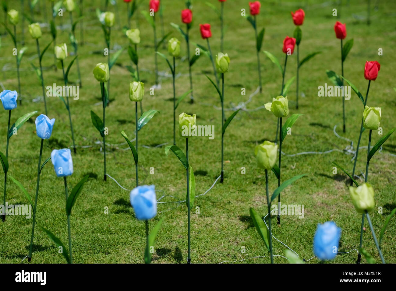 Green field with artificial flowers Stock Photo