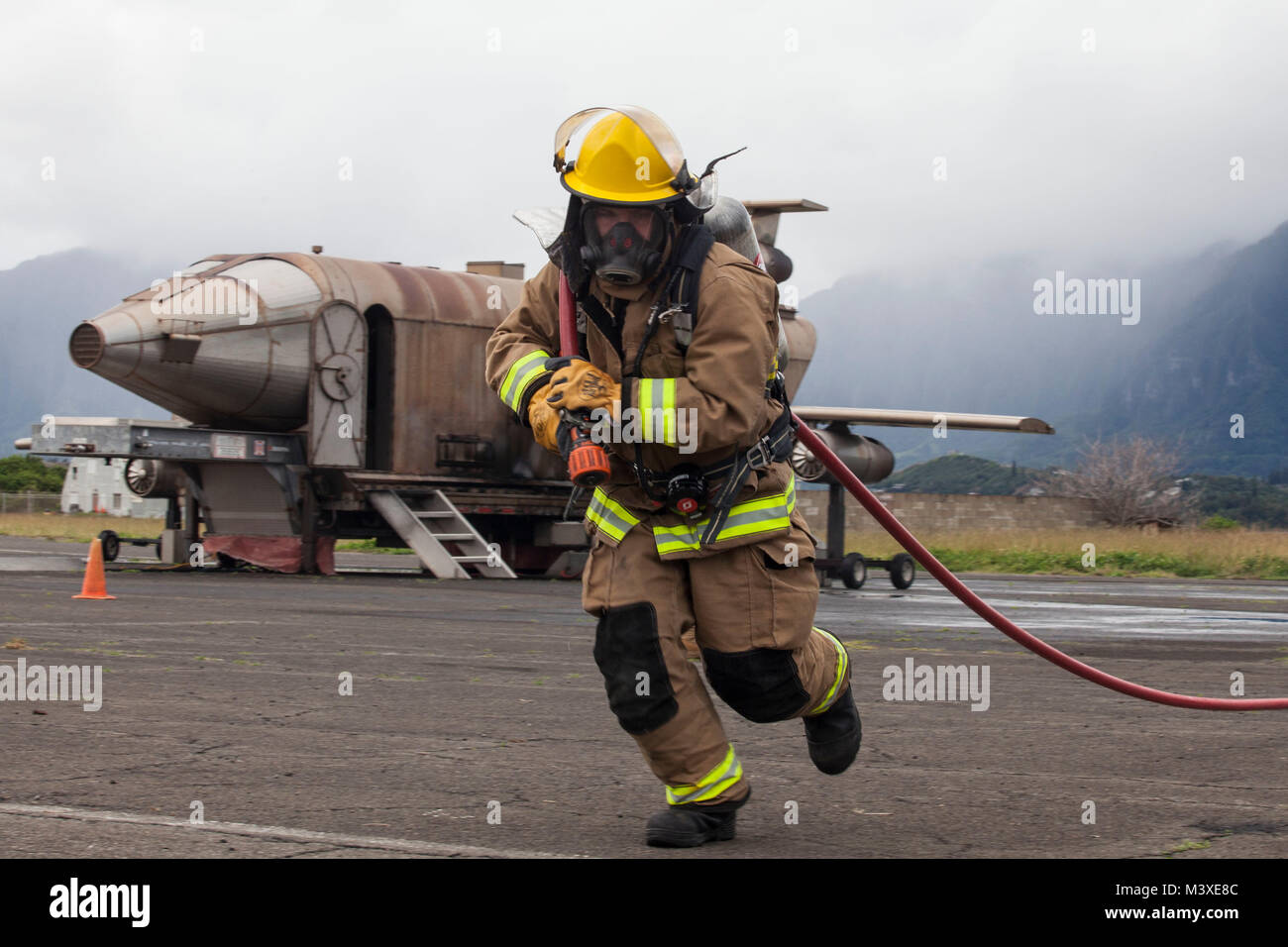 A U.S. Marine with Aircraft Rescue Fire Fighting (ARFF) unrolls a firehose during a wheel fire exercise at West Field, Marine Corps Air Station, Feb. 2, 2018. ARFF conducted a wheel fire exercise to improve proficiency in assessing and extinguishing a fire by utilizing the Mobile Aircraft Firefighting Training Device. (U.S. Marine Corps photo by Cpl. Jesus Sepulveda Torres) Stock Photo