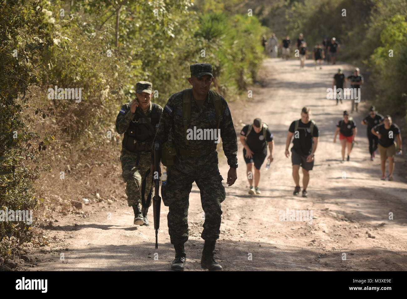 Two Honduran Soldiers hike the road to Las Minitas, a village located approximately three miles from Ajuterique in Comayagua, Honduras, while providing security to the Joint Task Force – Bravo service members participating in the Chapel Hike-75, Feb. 3, 2018. (U.S. Army photo by Martin Chahin) Stock Photo