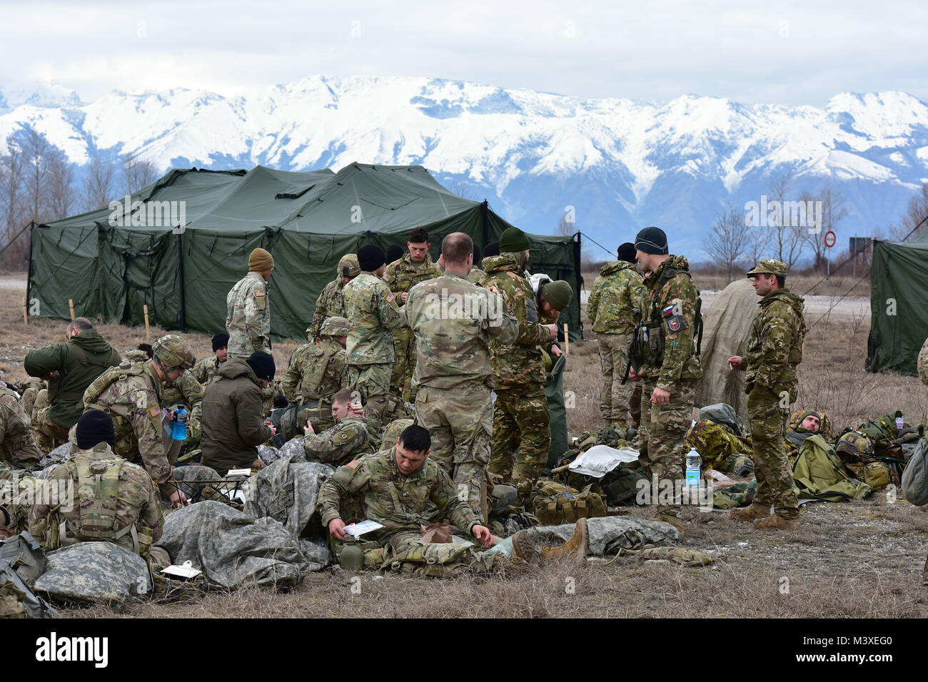U.S. Army Paratroopers assigned to the 1st Battalion, 503rd Infantry Regiment, 173rd Airborne Brigade, Italian Army Paratroopers from Brigata Julia Paracadutisti Alpini and the Brigata Folgore and Slovenian Army Soldiers relax after a land navigation event during the weeklong testing for the Expert Infantryman Badge. The soldiers must complete a number of prerequisites and pass a battery of graded tests on basic Infantry skills, Feb. 6, 2018 at Cellina Meduna area, Pordenone, Italy. (U.S. Army Photo by Paolo Bovo) Stock Photo