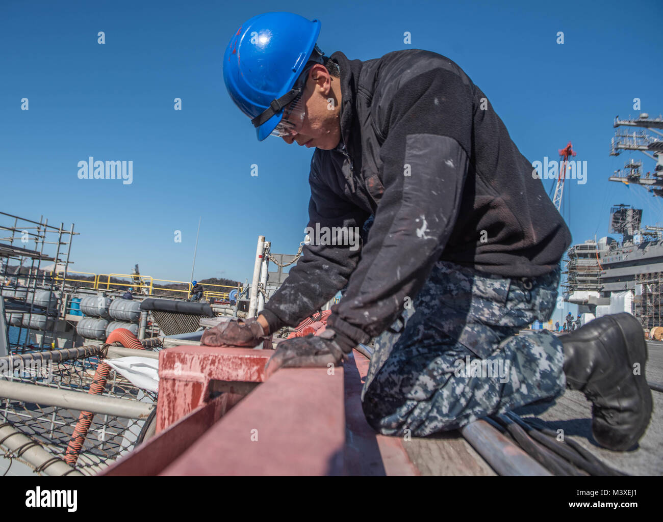 180206-N-PJ626-191  YOKOSUKA, Japan (Feb 6, 2018) Aviation Boatswain Mate (Handling) Airman Apprentice Vigil Juwa sands away corrosion from the flight deck aboard the Navy's forward-deployed aircraft carrier, USS Ronald Reagan (CVN 76), during the ship's selected restricted availability. Ronald Reagan, the flagship of Carrier Strike Group 5, provides a combat-ready force that protects and defends the collective maritime interests of its allies and partners in the Indo-Asia Pacific region. (U.S. Navy photo by Mass Communication Specialist 3rd Class Kaila Peters/Released) Stock Photo