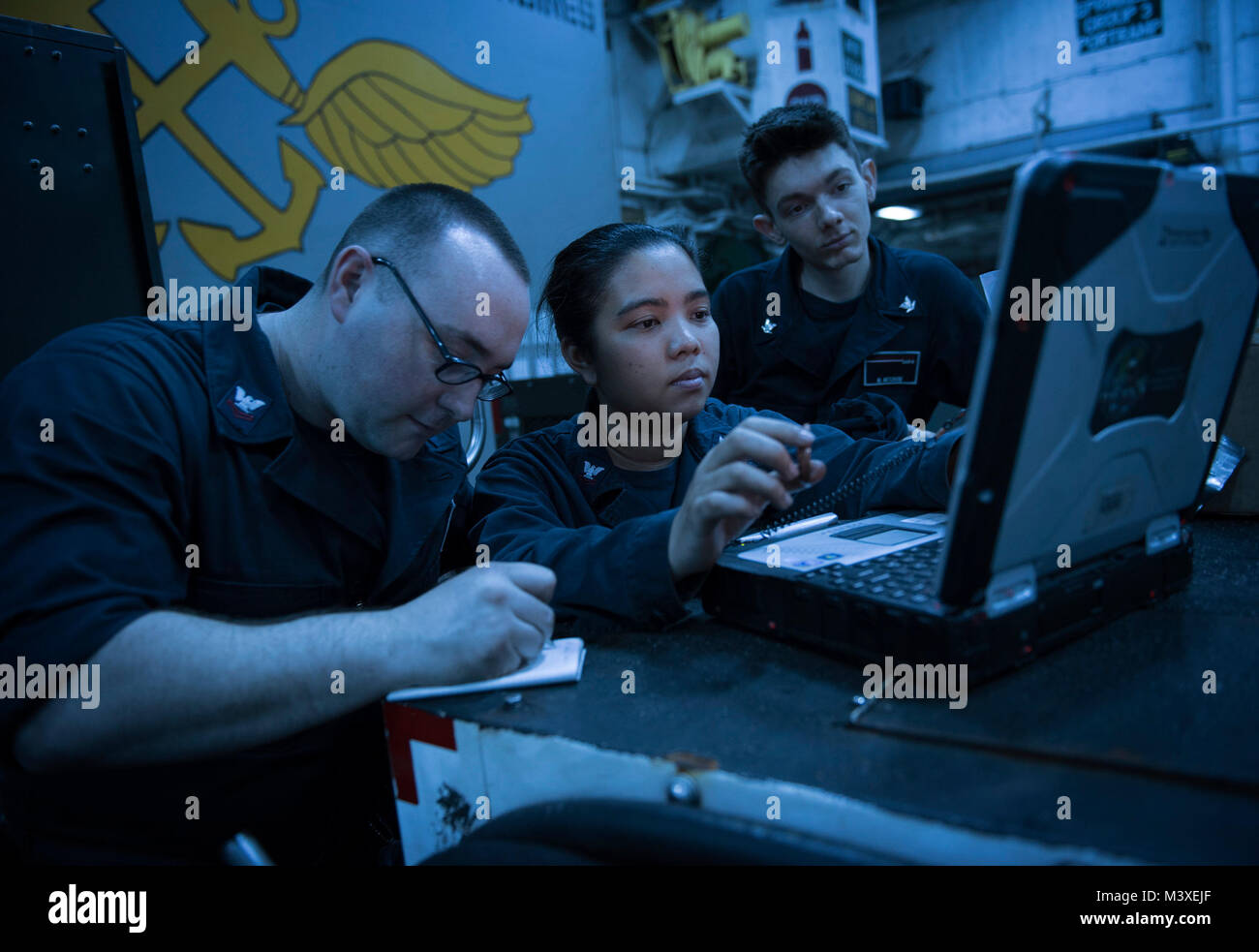 180206-N-WF272-150 SOTUH CHINA SEA (Feb. 6, 2018) Aviation Support Equipment Technician 2nd Class Daniel Carrigan, left, from Warwick, Ill., Aviation Support Equipment Technician 2nd Class Vanessa Castro, center, from San Diego, and Aviation Machinist’s Mate 3rd Class Moses Mitchum, from Oklahoma City, verify parts used during equipment maintenance in the hangar bay of the amphibious assault ship USS Bonhomme Richard (LHD 6). Bonhomme Richard is operating in the Indo-Asia-Pacific region as part of a regularly scheduled patrol and provides a rapid-response capability in the event of a regional  Stock Photo