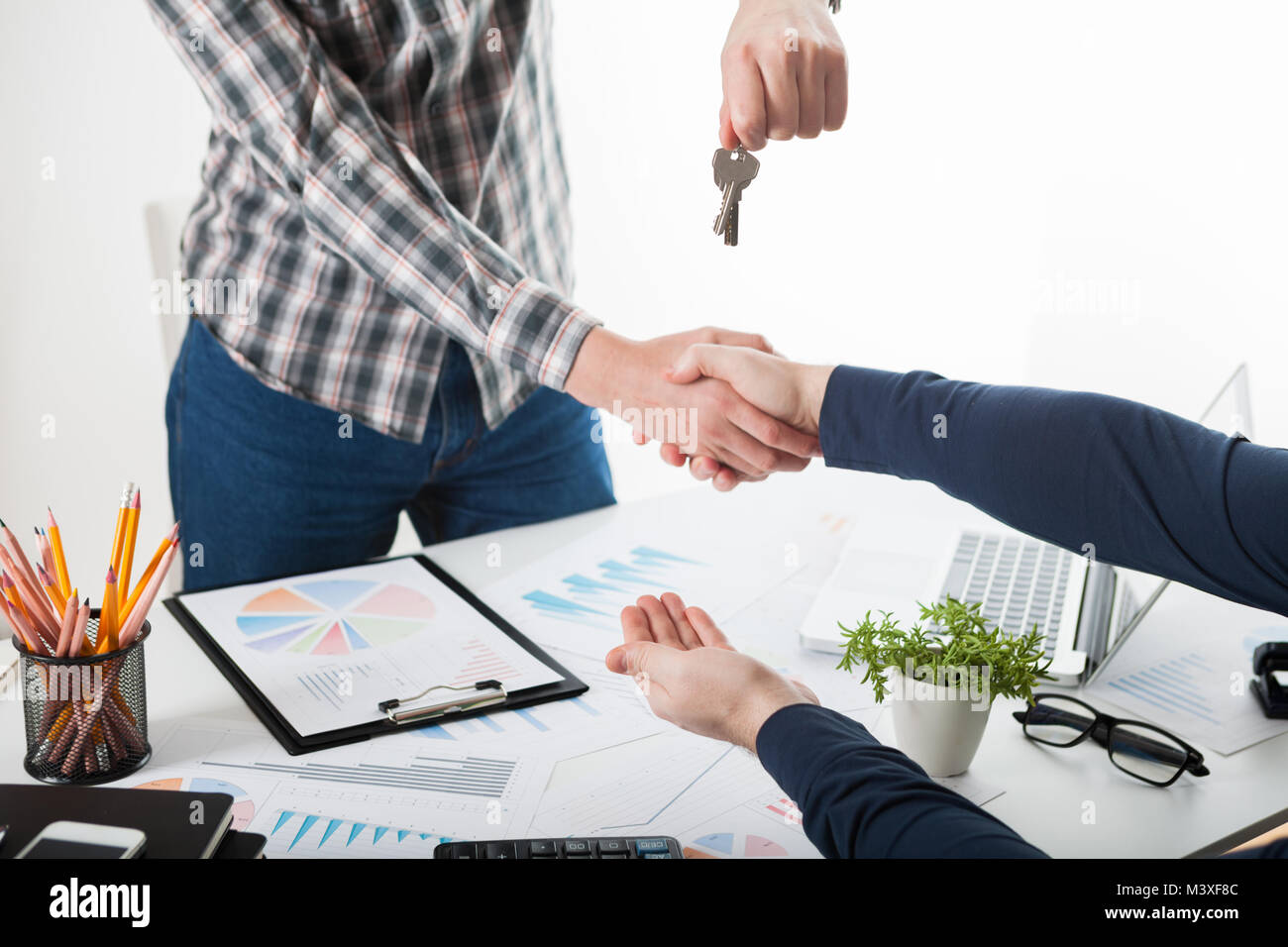 Two business person shaking hands only hands to be seen and a key is be ...
