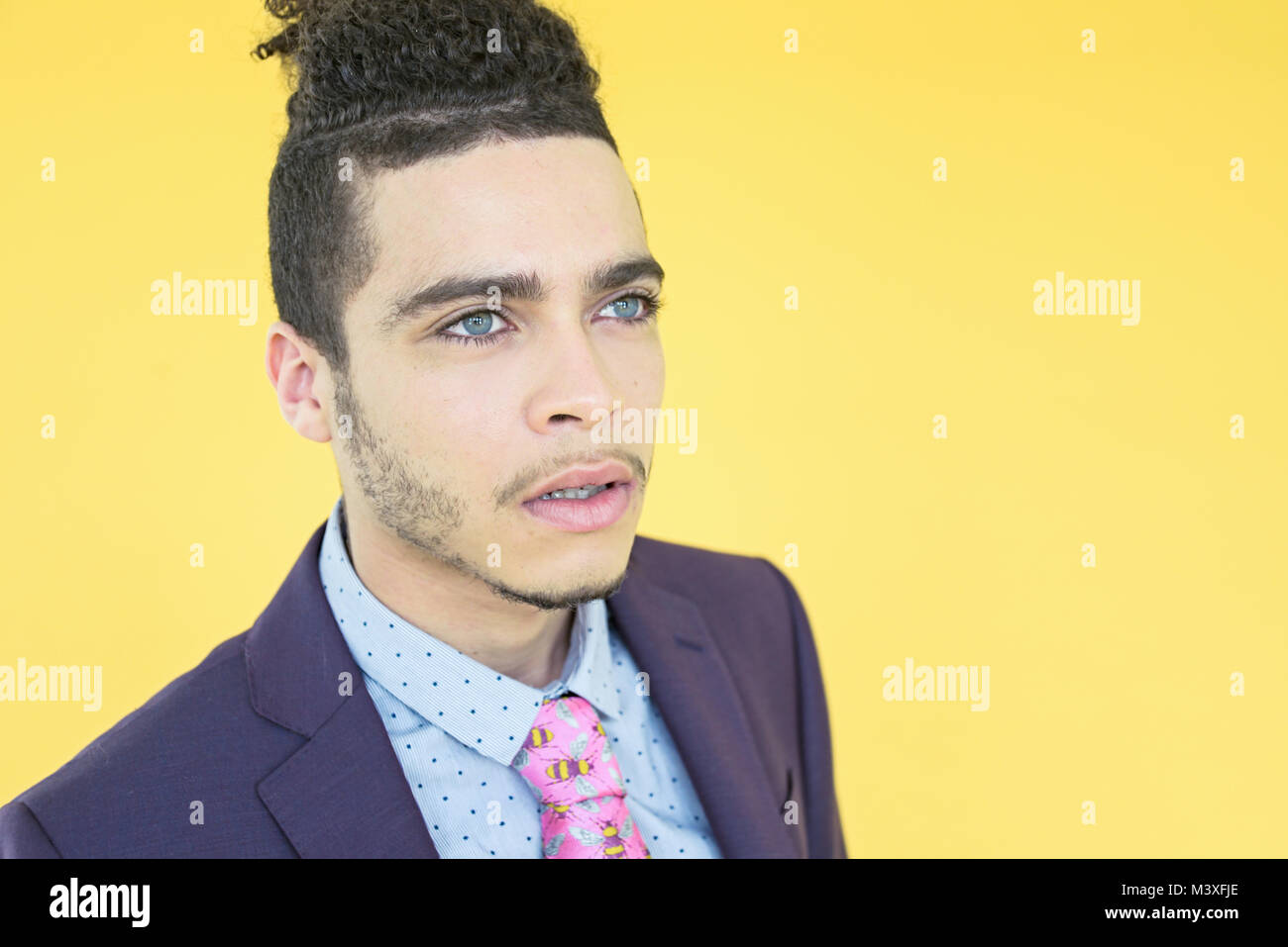 Handsome mixed race young man in a trendy purple suit isolated on yellow background Stock Photo