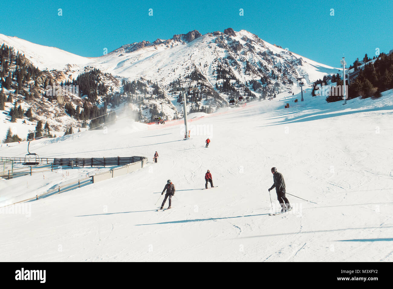 Skiers and snowboarders riding on a ski slope mountain resort on snowy winter background. tinted retro photo. ski resort Shymbulak Stock Photo
