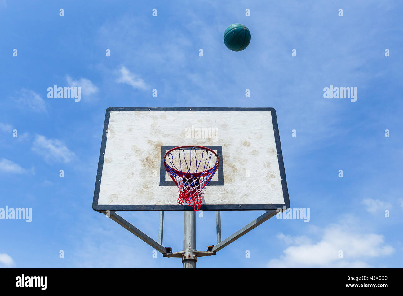 Basketball blue ball flight towards board and net against sky outdoor court Stock Photo