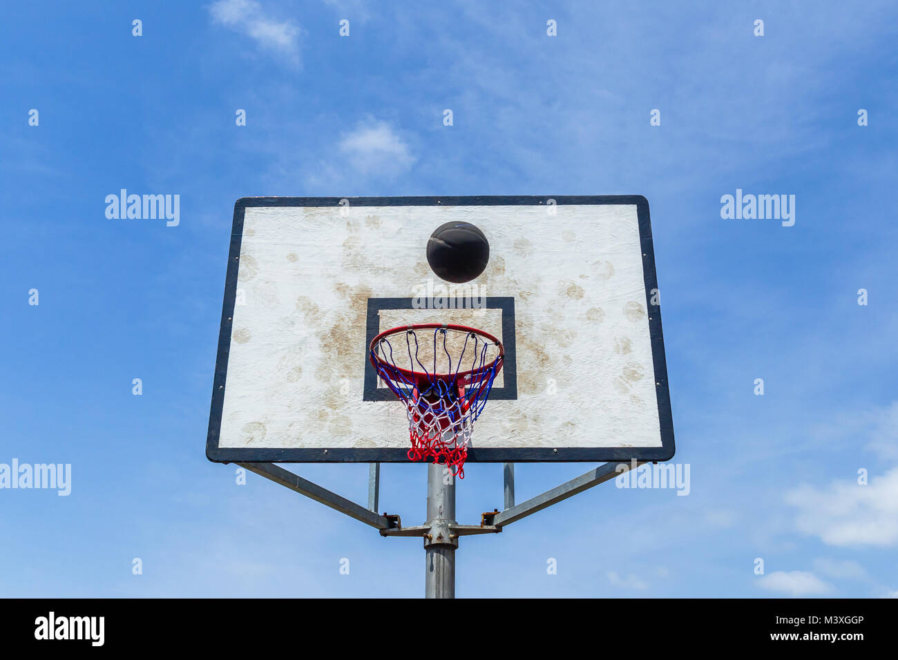 Basketball ball flight against board and net against sky outdoor court Stock Photo
