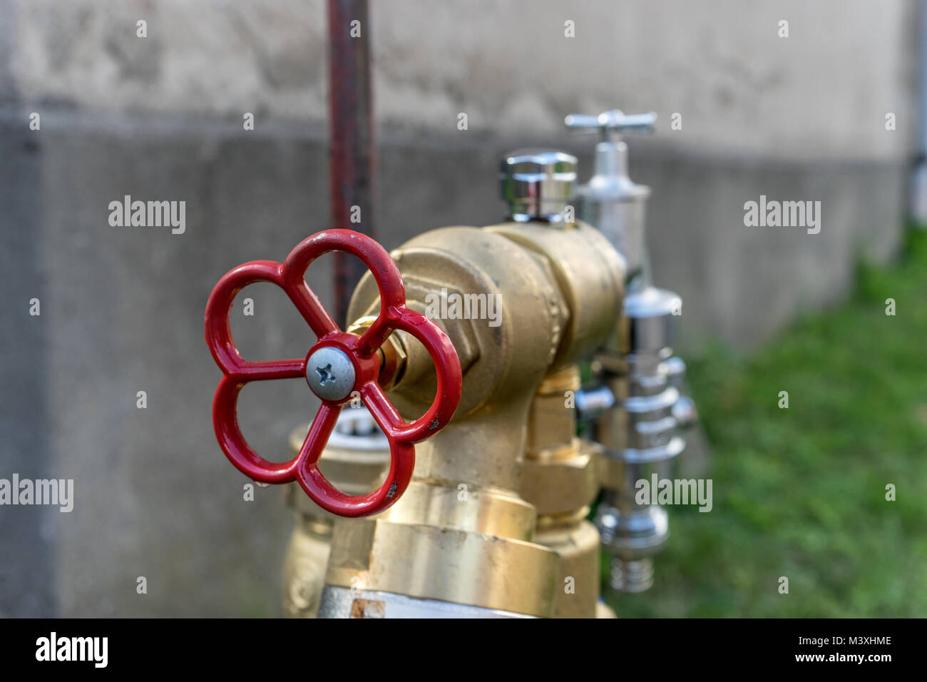 Water connection with a red wheel in front of a house wall Stock Photo