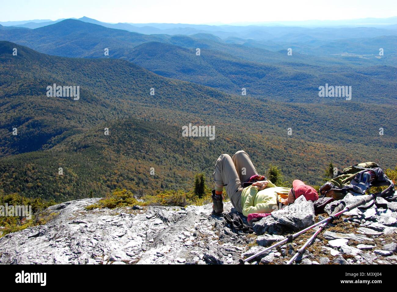 Hiker relaxing on Mt. Mansfield, Vermont, in the fall. Camel's Hump mountain in the distance. Stock Photo