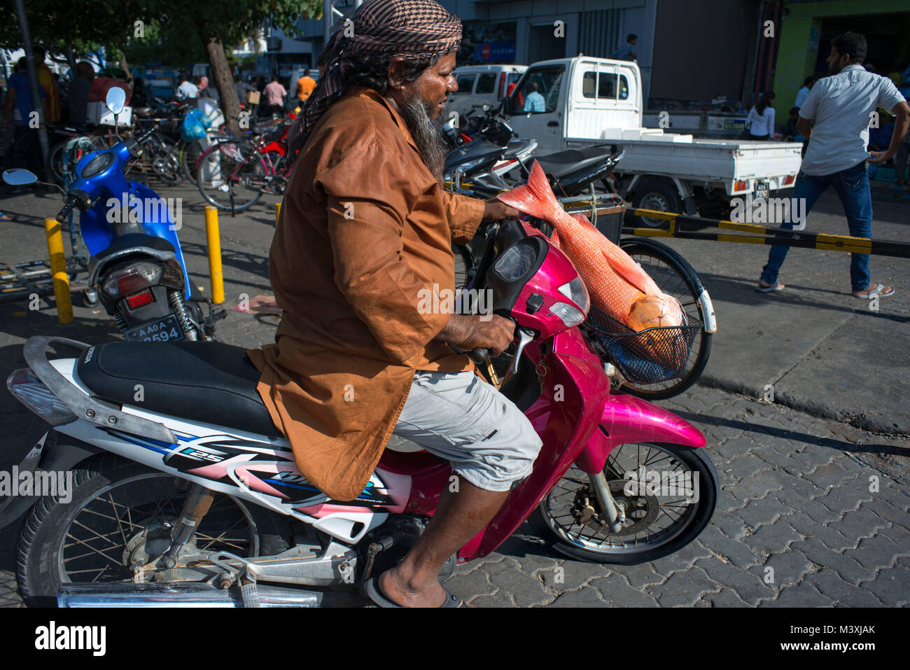 Man in a motorcicle with a big tropical fish. Harbour of Male city, Male Island, North Male Atoll, Maldives. Stock Photo