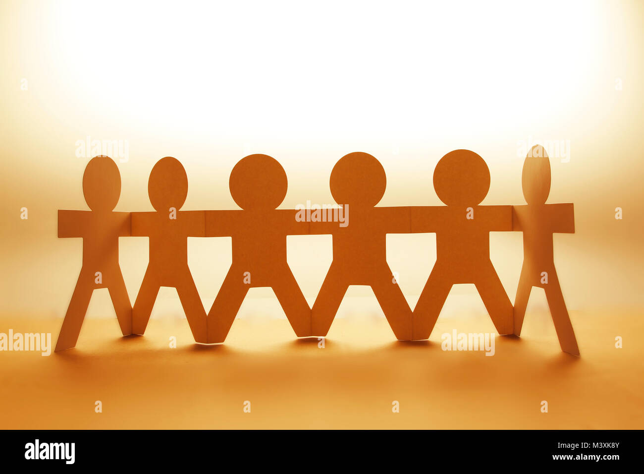 Team of paper chain people in a row holding hands Stock Photo - Alamy