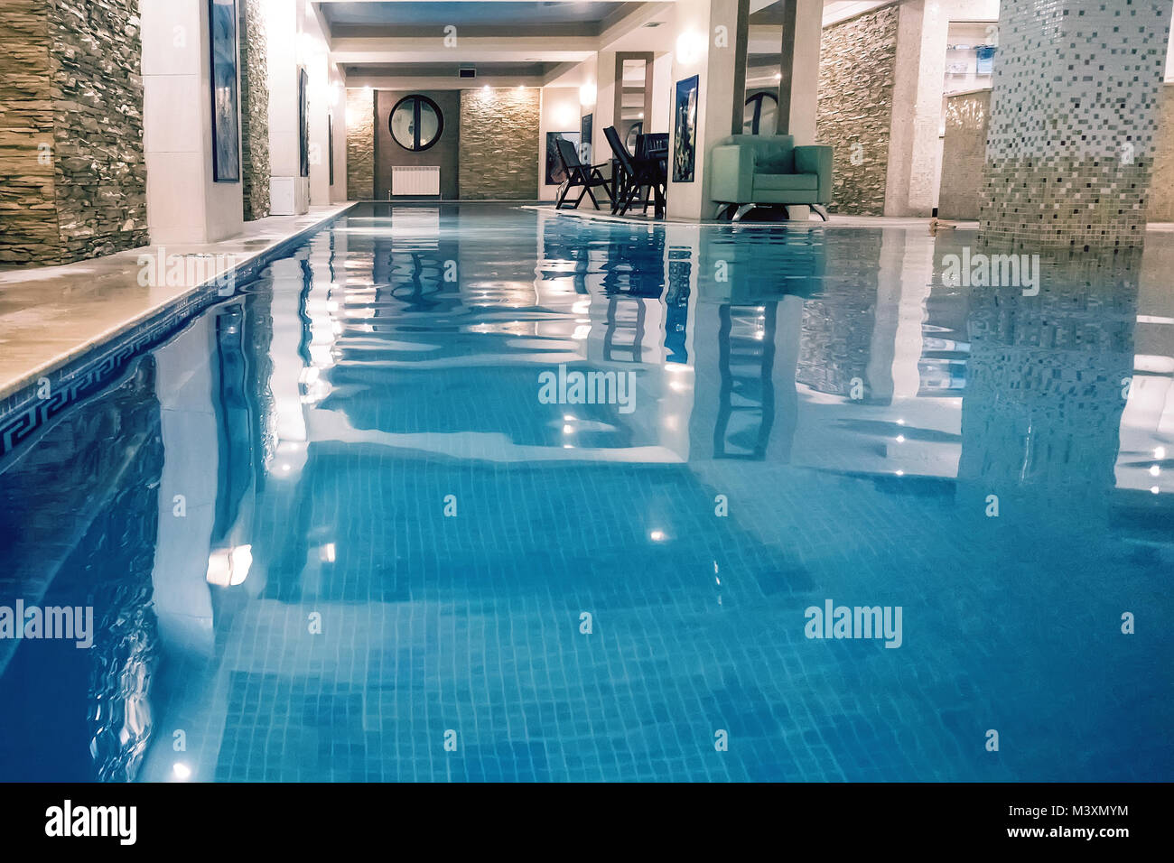 Indoor swimming poo on resort. Spa and Wellness centre with swimming pool, bath, sauna, and restaurant inside. Swimming pool with blue clear transpare Stock Photo