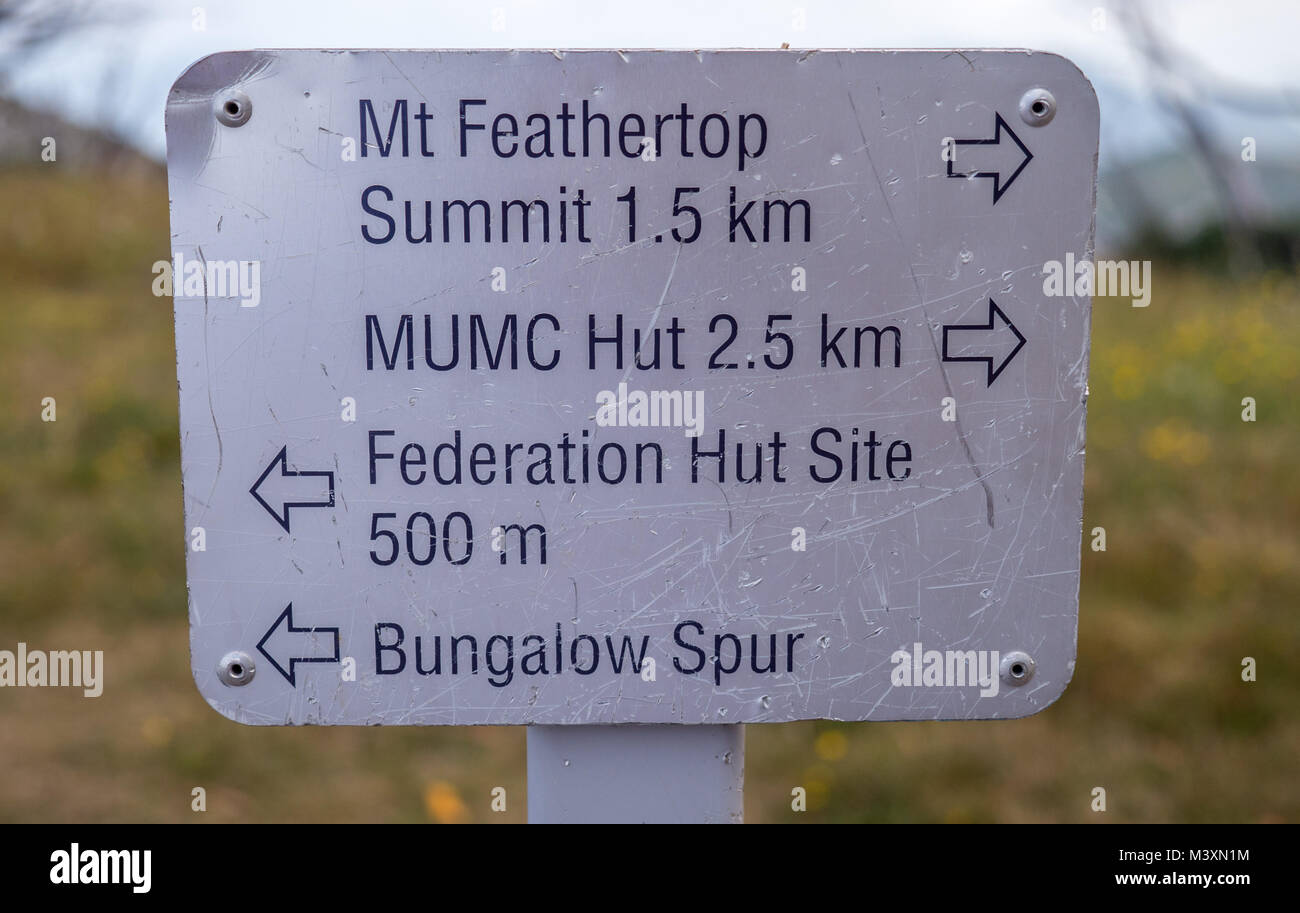 Small metal Mt Feathertop summit trail marker sign with hut and tail directions blurry background. Stock Photo