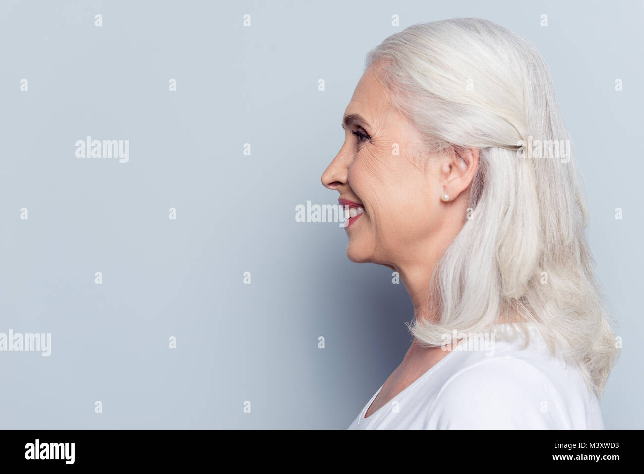 Close up profile, half face portrait with copy space of cheerful, happy, aged, mature, nice woman   over gray background Stock Photo