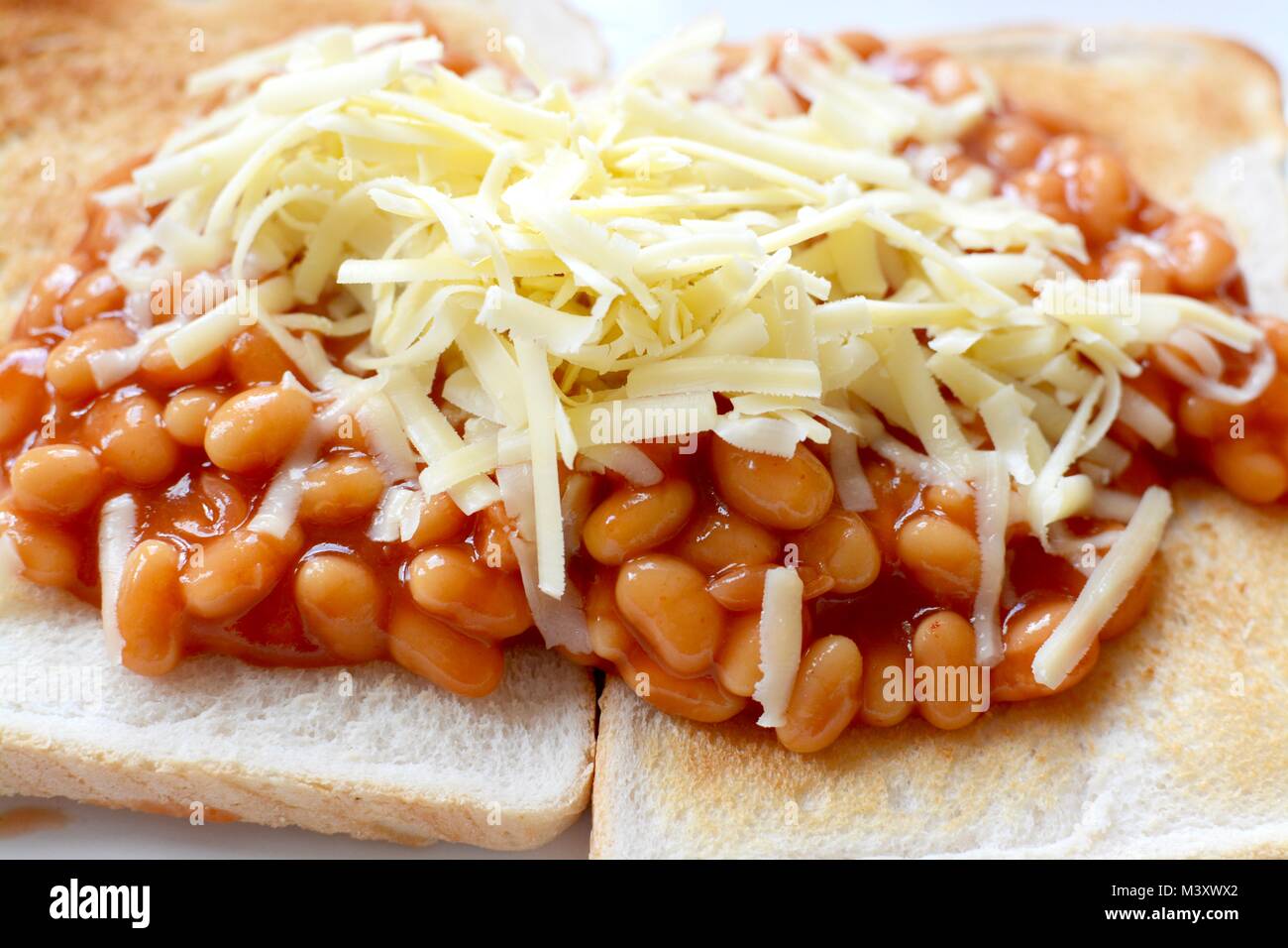 Baked beans on white toast topped with grated cheddar cheese Stock