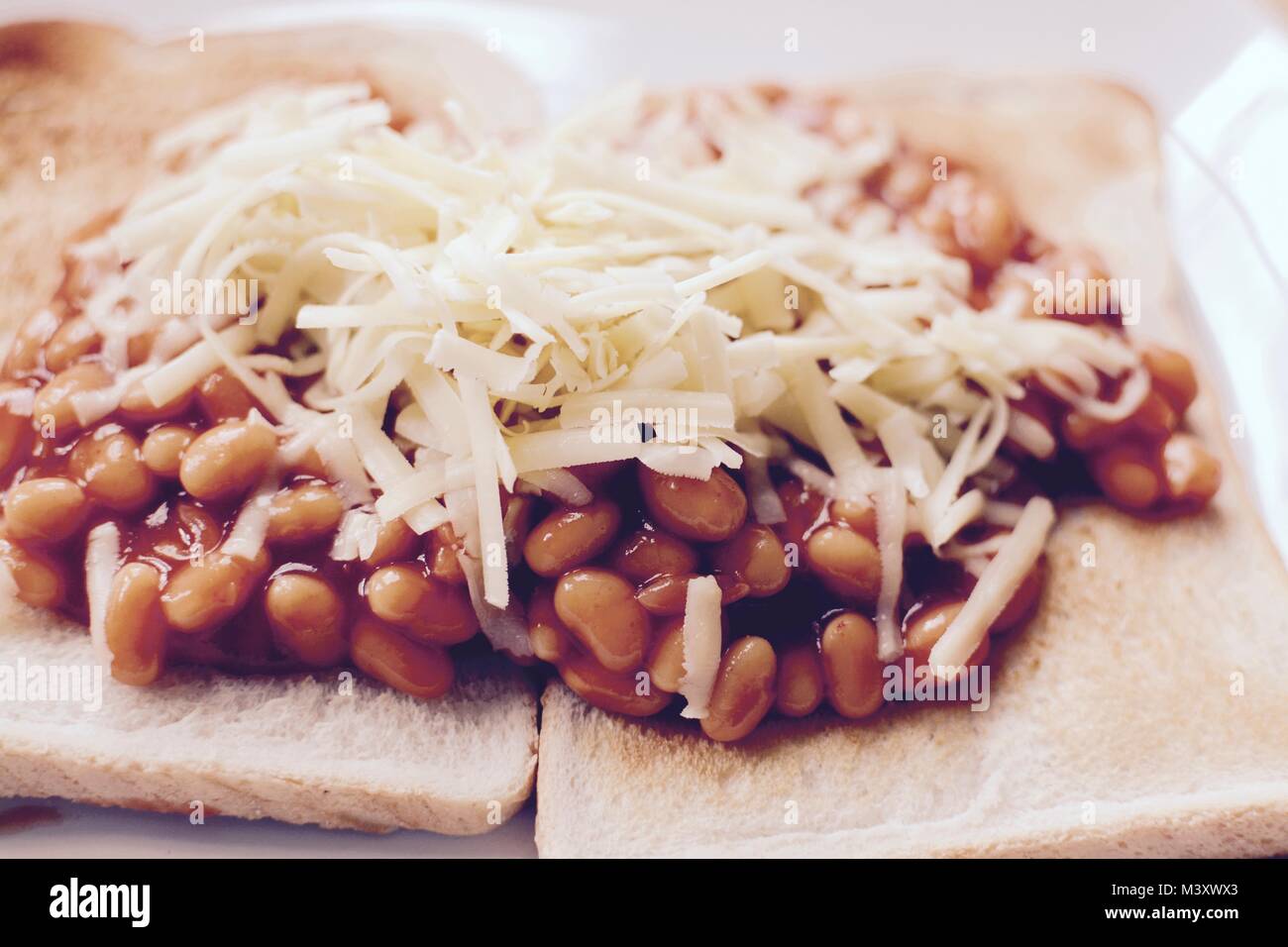 Baked beans on white toast topped with grated cheddar cheese - filter applied Stock Photo