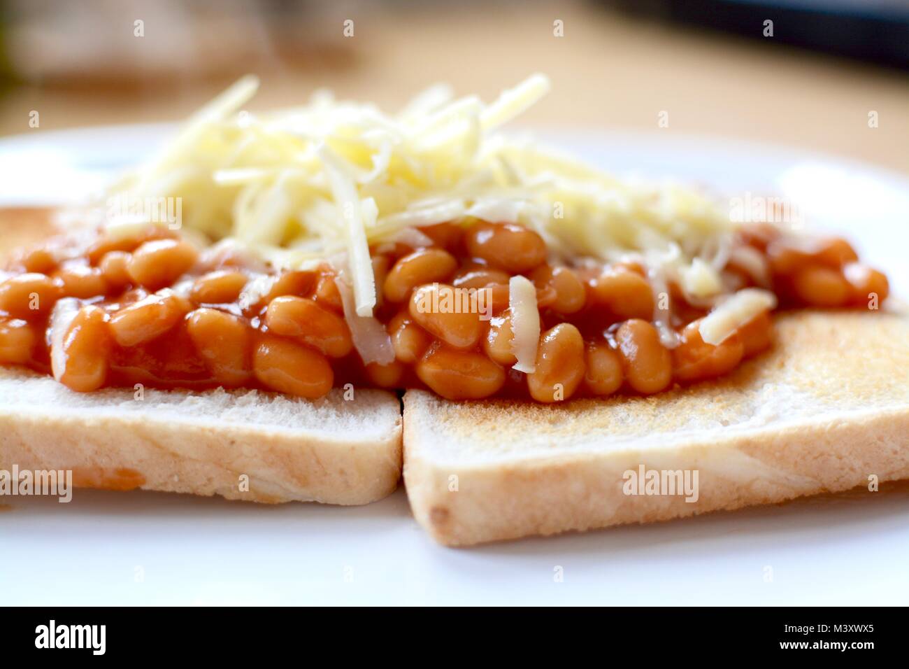 Baked beans on white toast topped with grated cheddar cheese Stock Photo