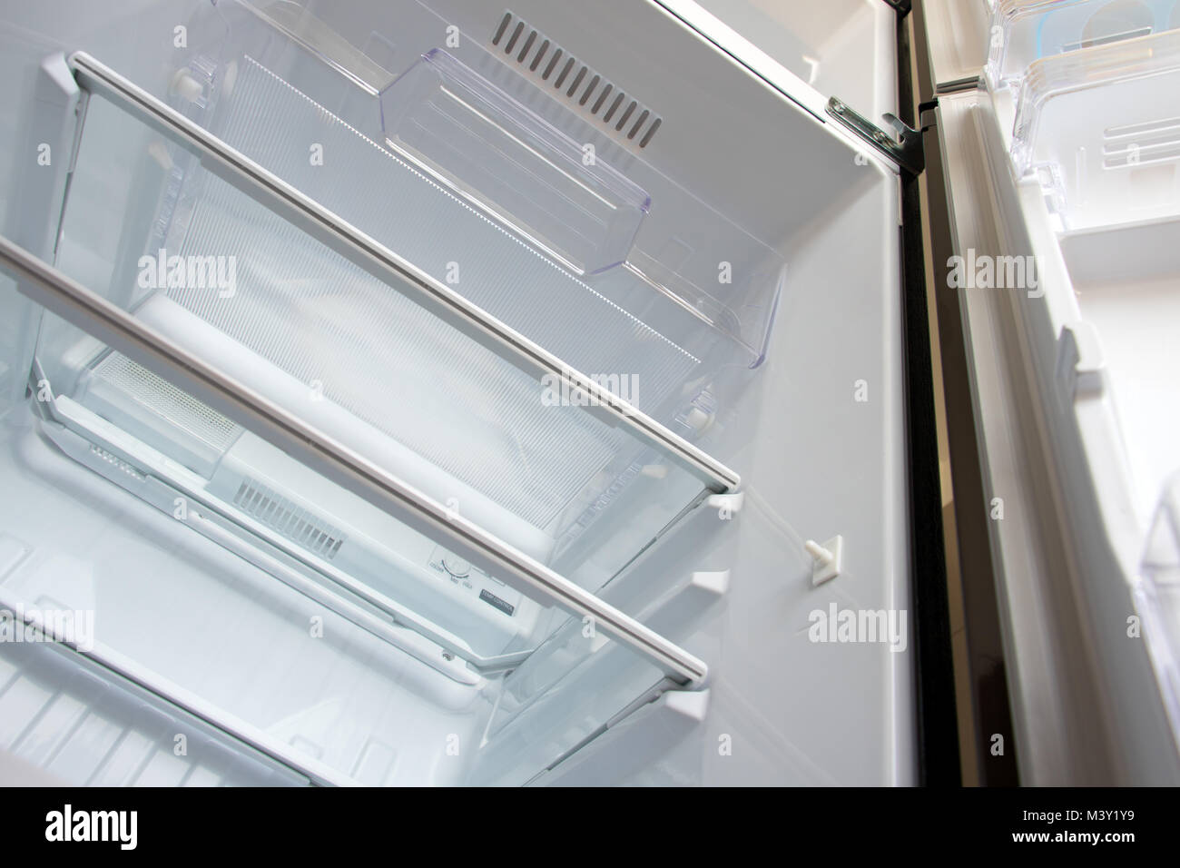 Open new fridge. Empty refrigerator with open door, view from below. Stock Photo