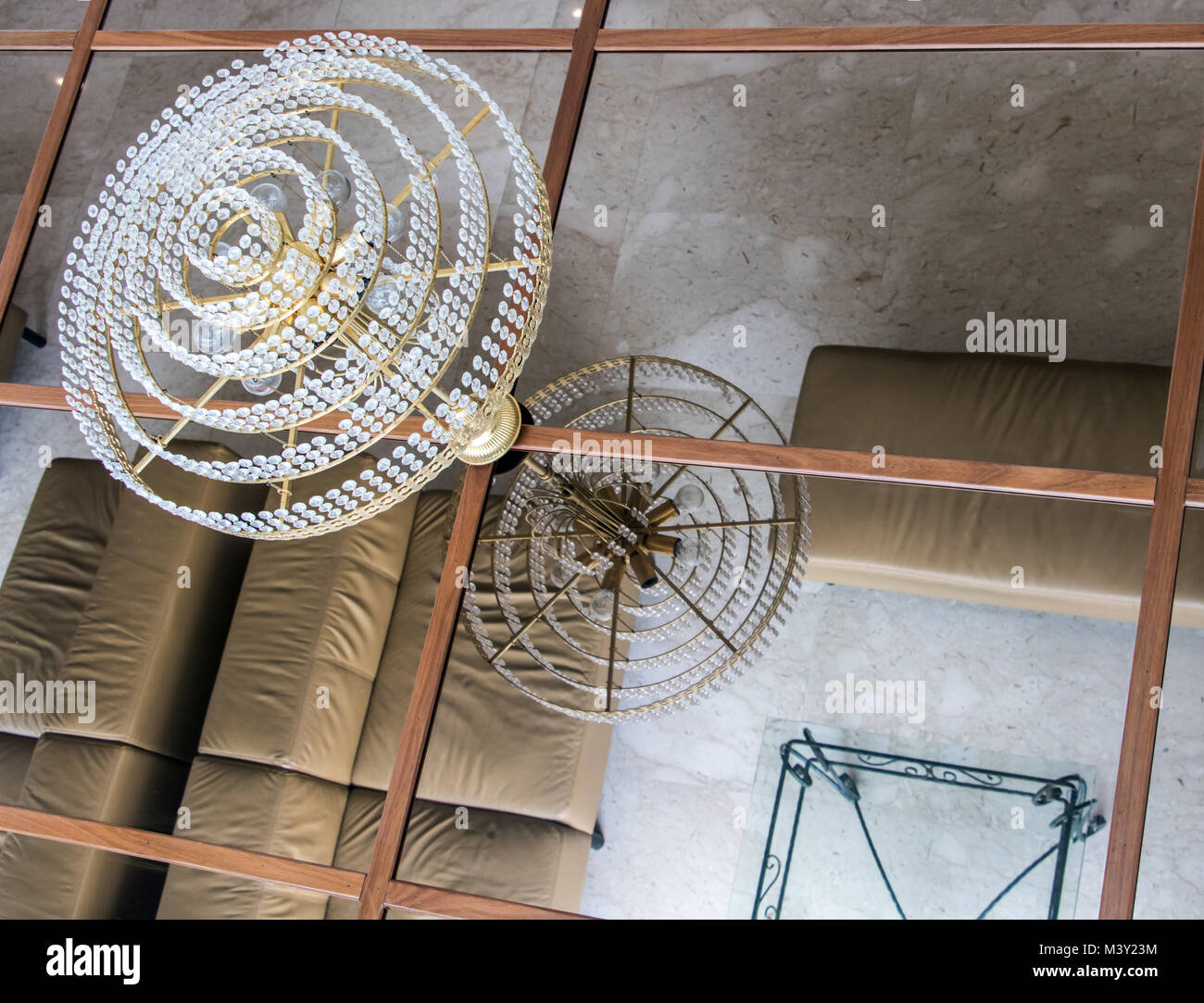 The chandelier hangs from the ceiling with mirrors in a room with armchairs. Mirroring room in