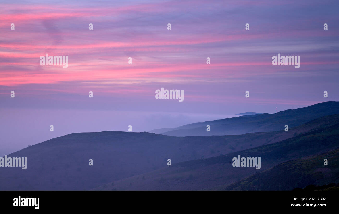 Mist on the Clwydian range of mountains at dusk with colourful clouds Stock Photo