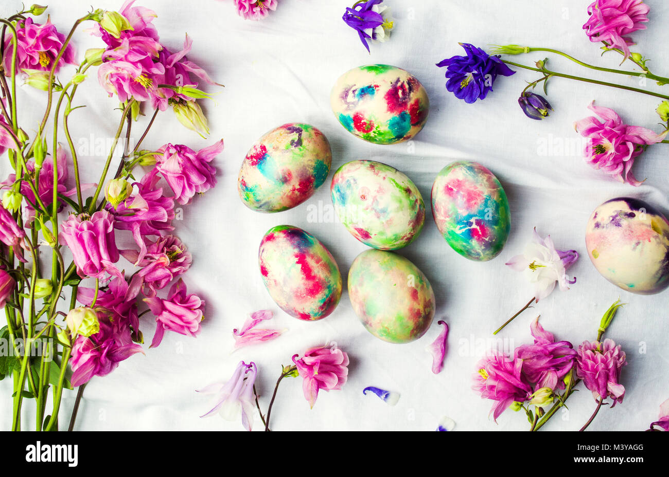 Easter eggs and colorful iris flowers on white textile background Stock Photo