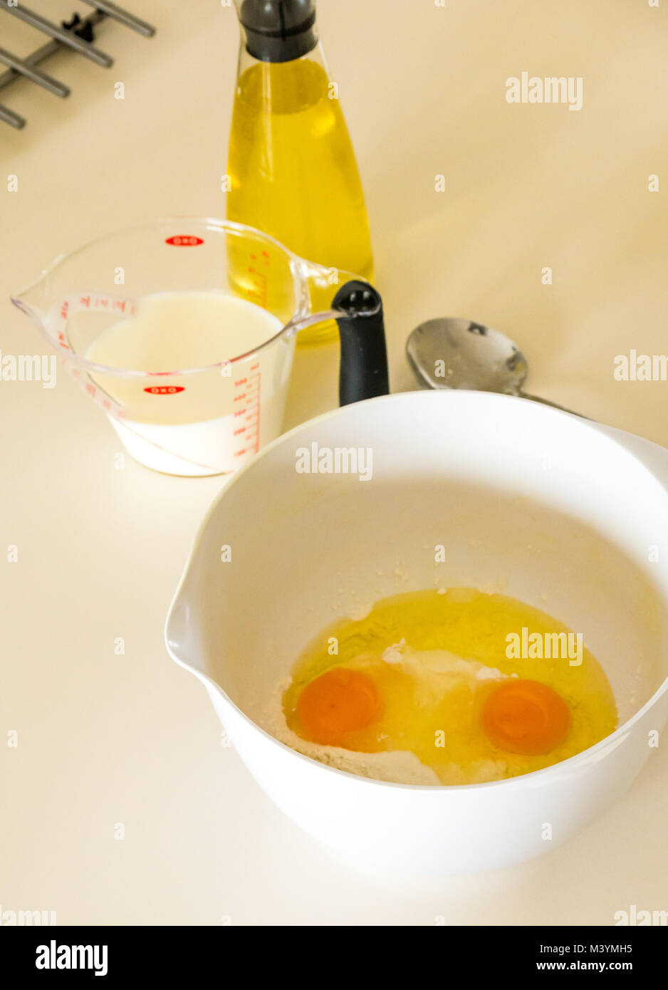 Preparation of pancake batter for Shrove Tuesday with flour, milk, eggs, and oil in a home kitchen Stock Photo