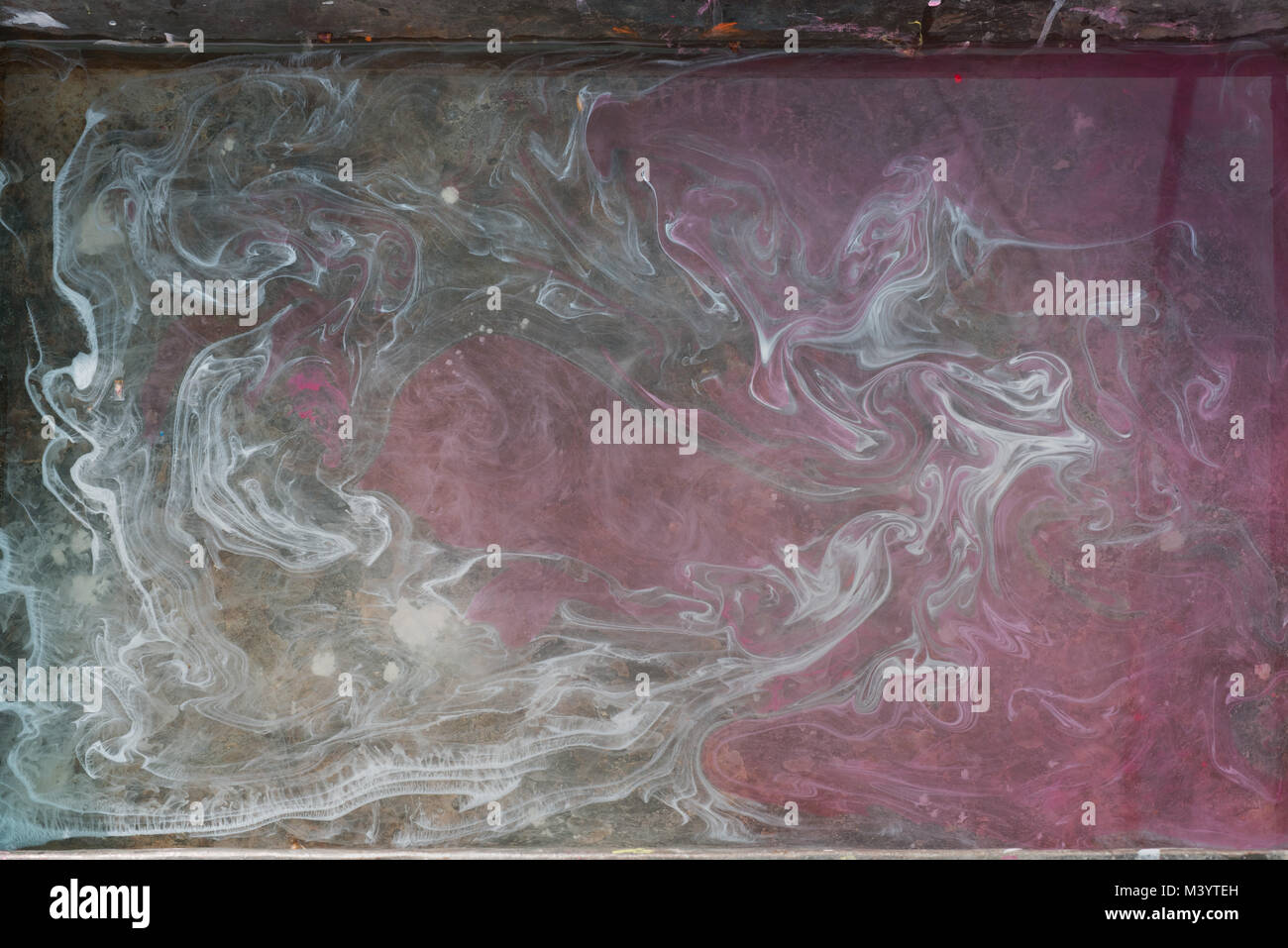 Abstract design background from a mixture of watercolor paints: the gray whirlwinds on the left break into a matte pink background. Stock Photo