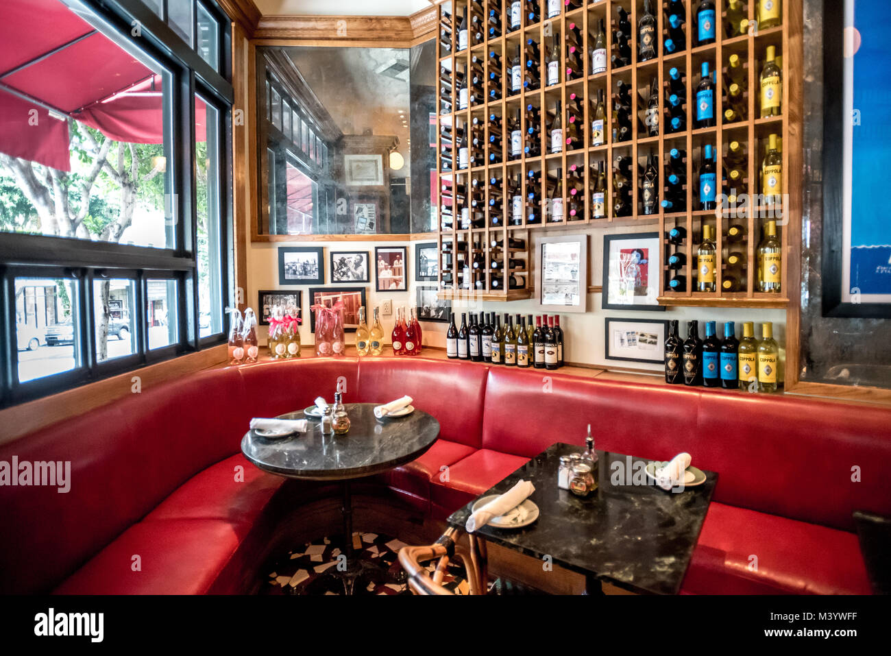 Cafe Zoetrope seating in flatiron angle corner of this wine bar restaurant and cafe in North Beach San Francisco with Coppola wine bottles in rack Stock Photo